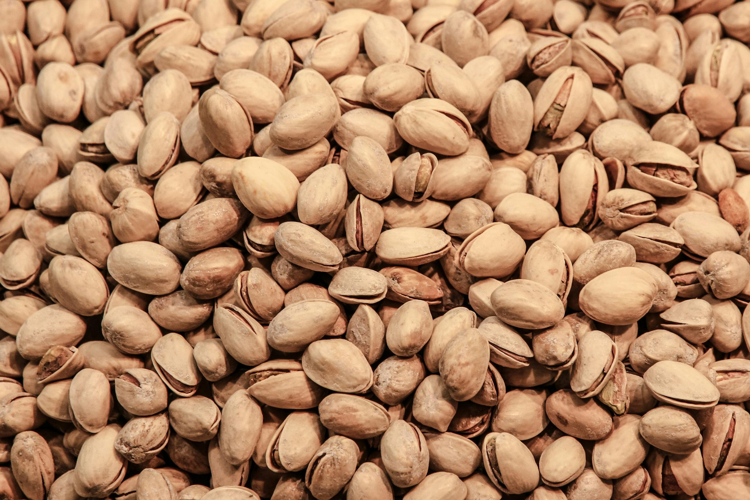 A detailed close-up image of pistachio nuts, showcasing their natural texture and earthy tones.