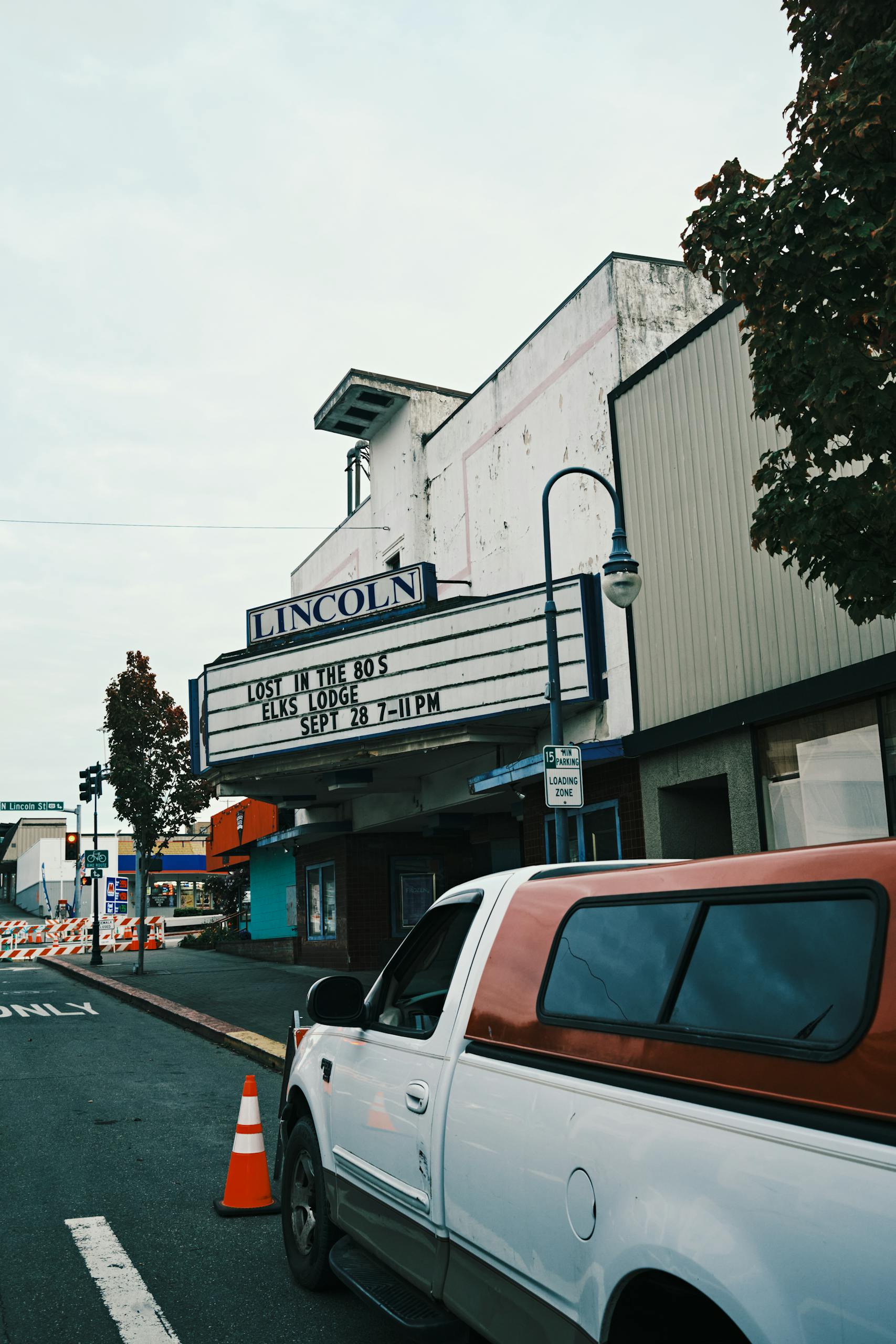 A city scene featuring the Lincoln Theater with its marquee sign and a parked truck in the foreground.