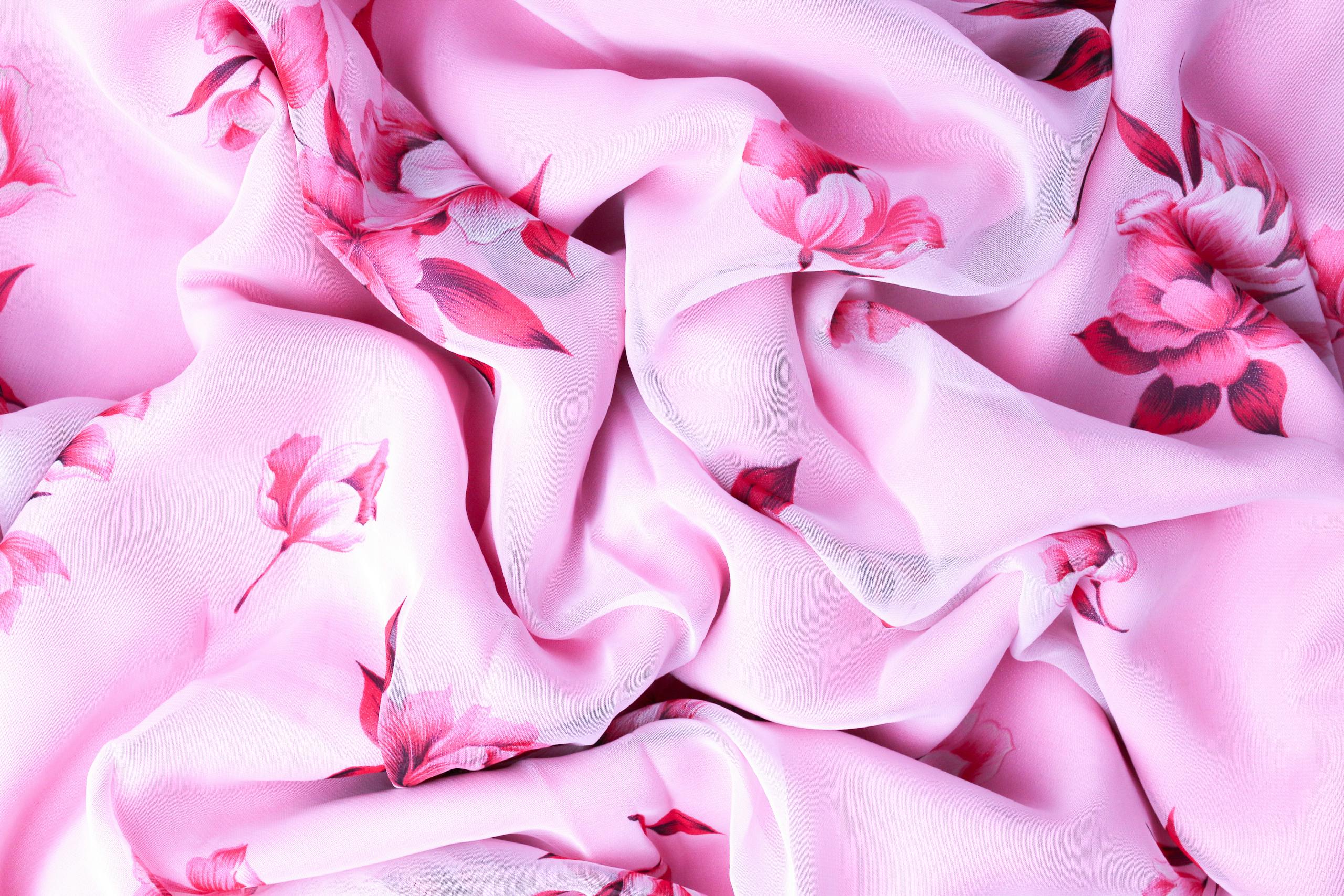 A delicate close-up of pink floral fabric, highlighting its soft texture and design.