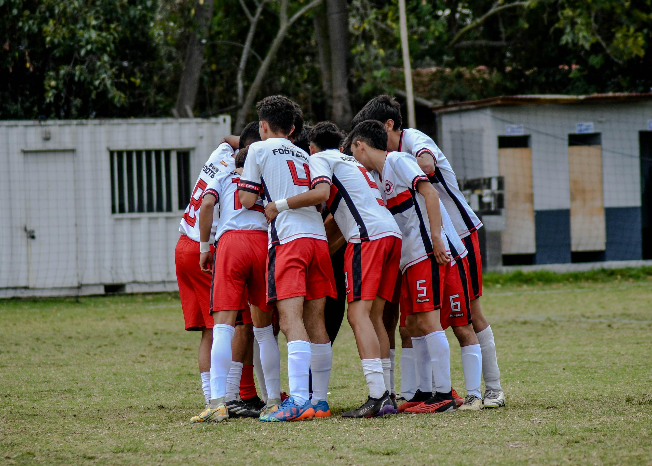 Young soccer players huddle on field in team uniform before game.