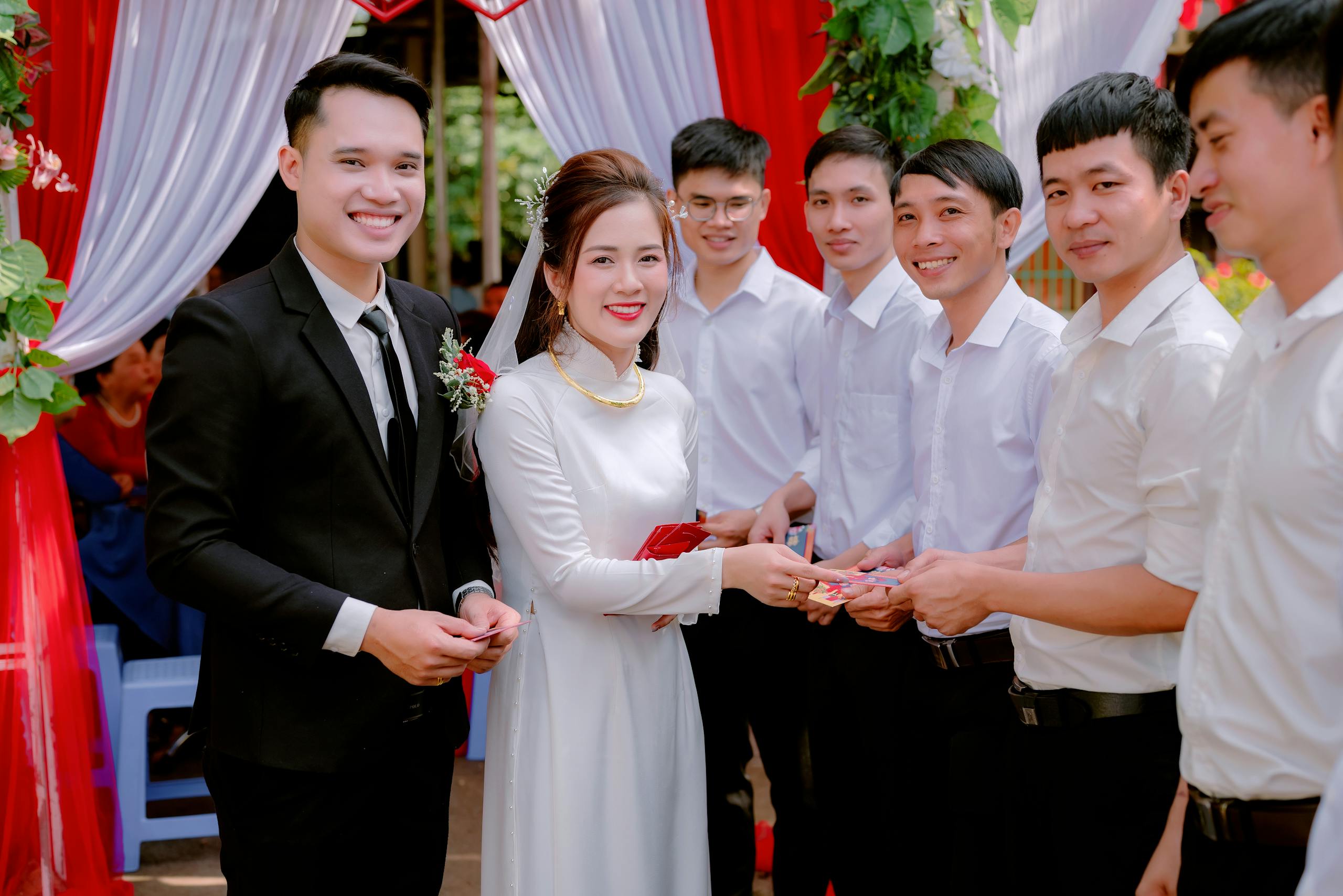 A beautiful wedding scene with a bride and groom exchanging gifts outdoors.