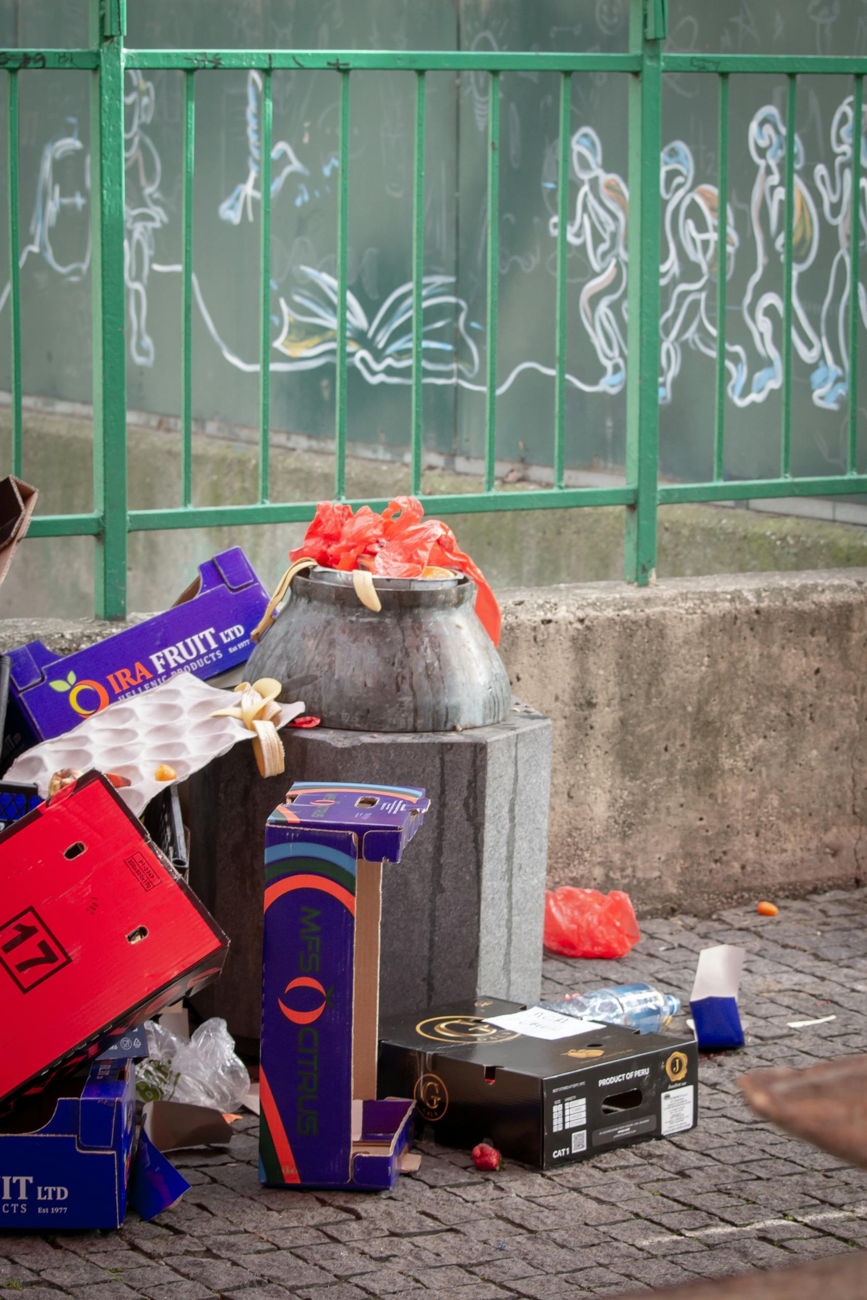 A cluttered urban street corner with empty boxes and a trash can. Urban decay.