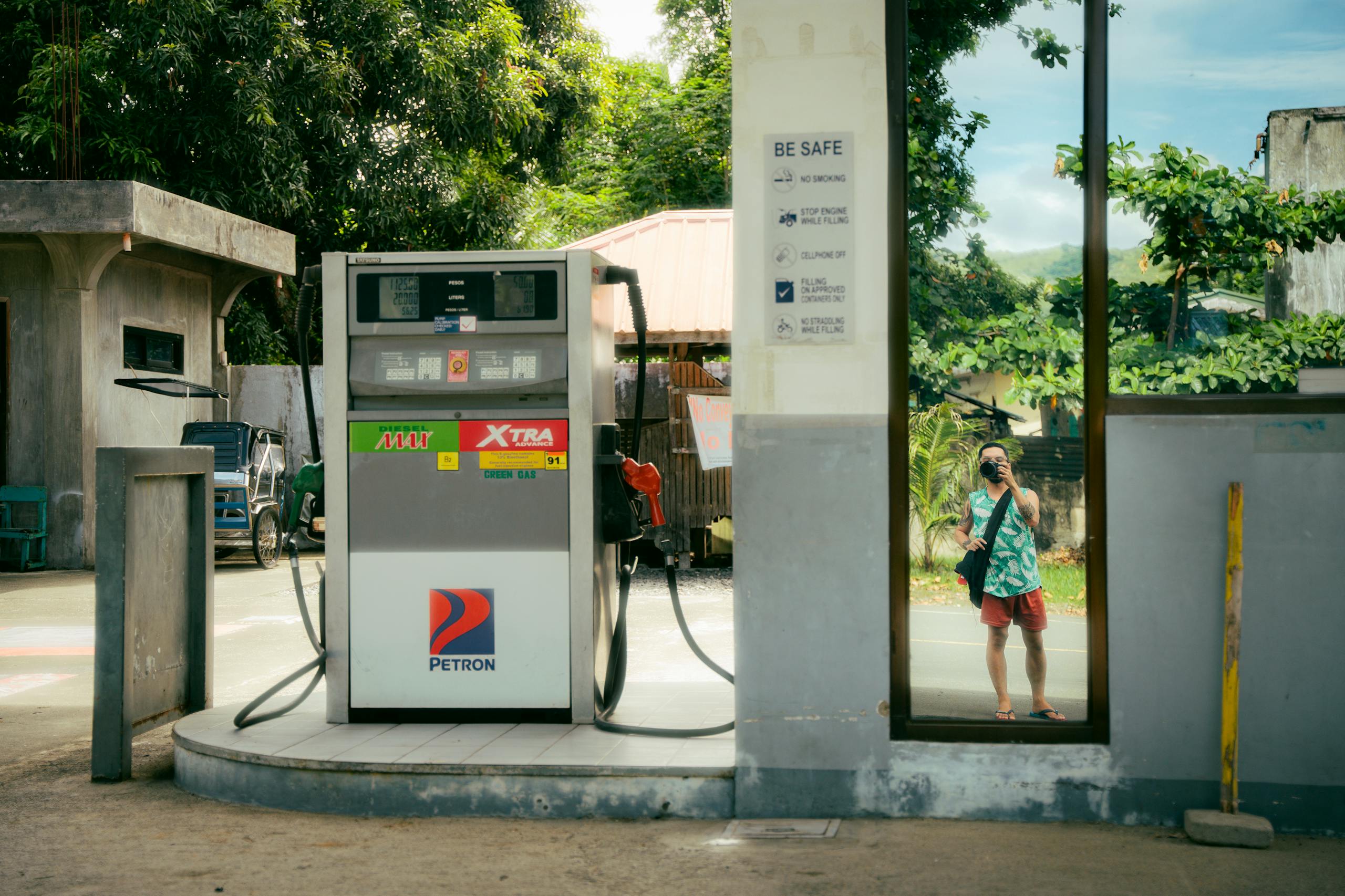 A gas station with a reflection of a person taking a selfie in a rural area.