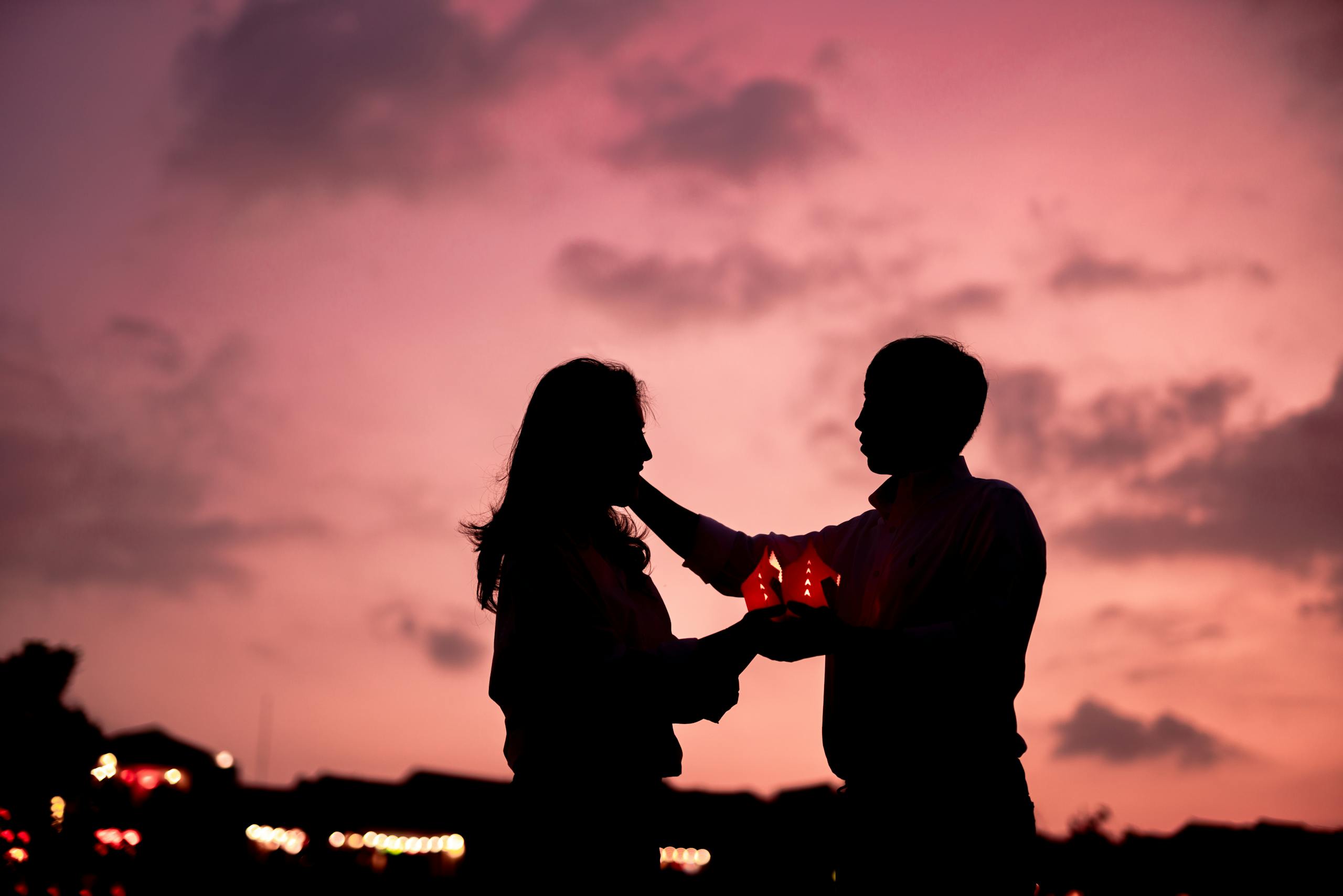 A romantic silhouette of a couple holding lanterns during a sunset, symbolizing love and connection.