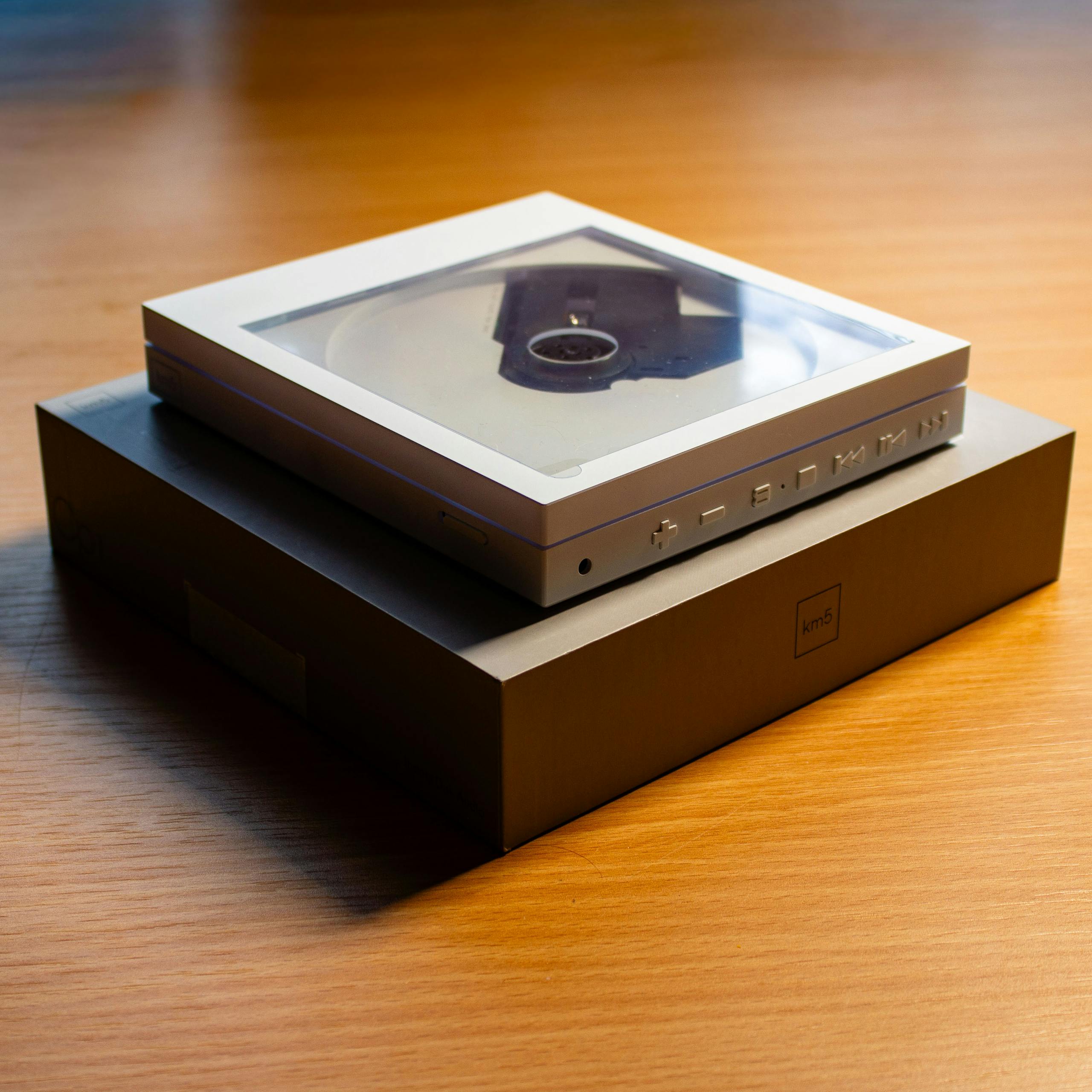 A sleek, modern CD player with clear display on a wooden table, showcasing minimalist design.