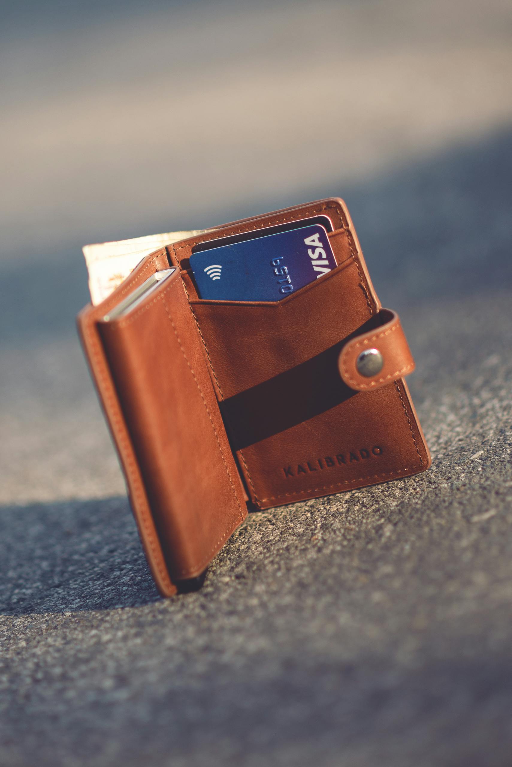 A stylish leather wallet with bank cards set on pavement, highlighting luxury and everyday use.