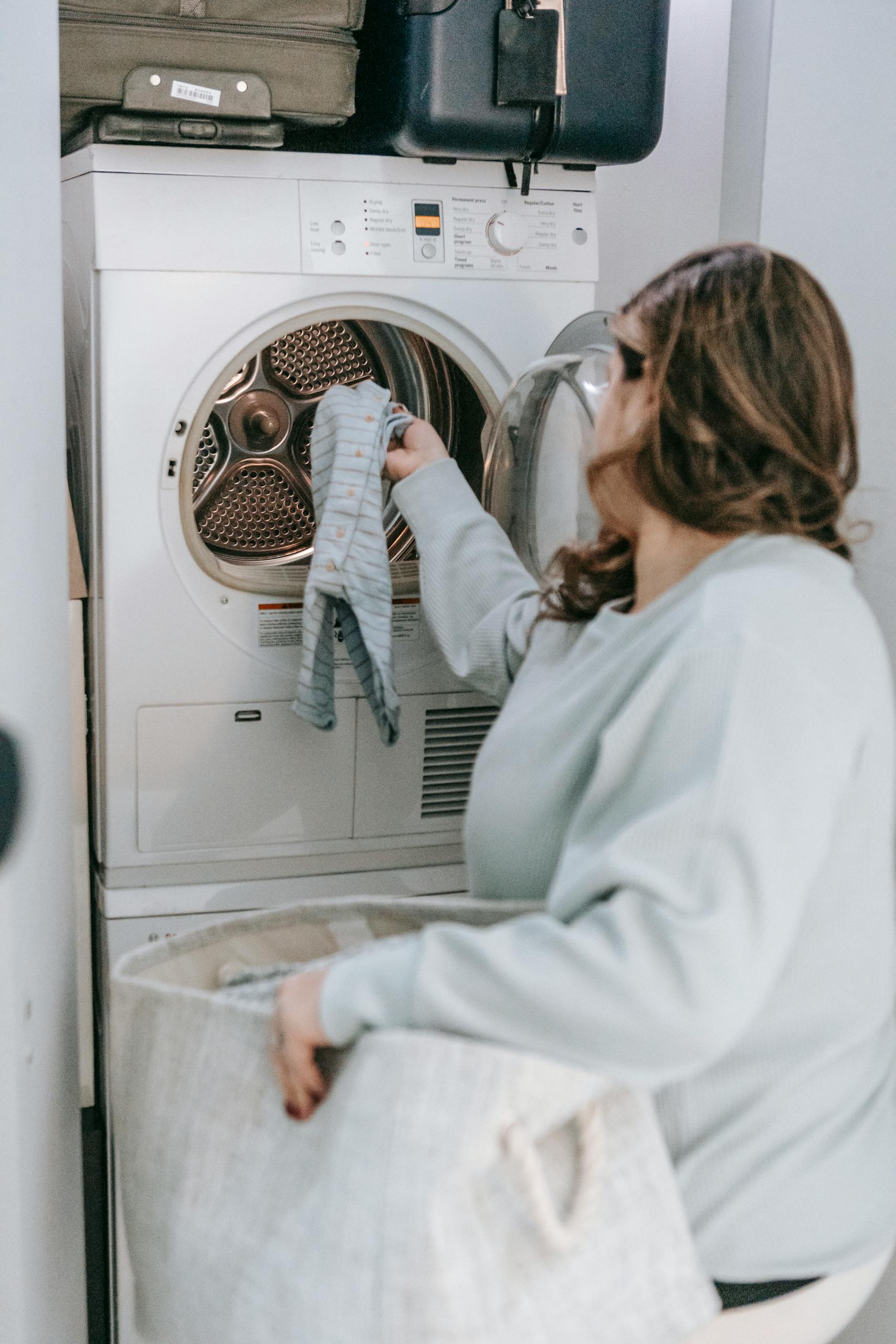 A woman handling laundry in a home laundry room setting.