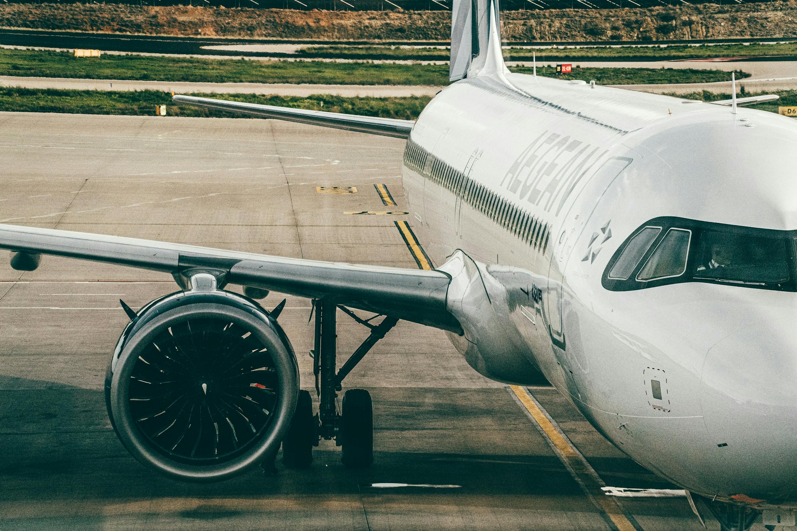 Aegean Airlines airplane parked on airport tarmac, showcasing the aircraft's engine and fuselage.