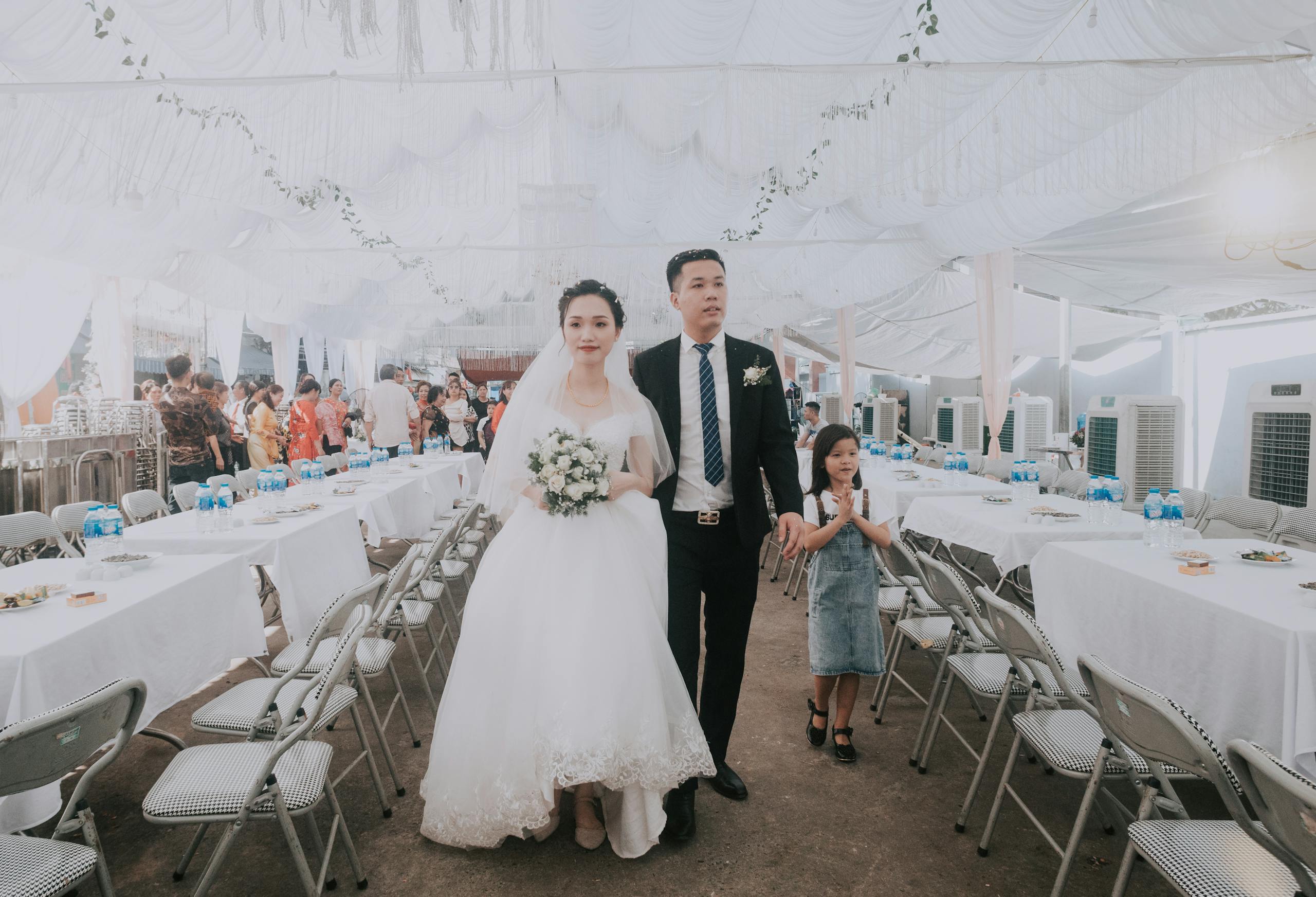 Bride and groom walking down the aisle at an elegant indoor wedding ceremony with guests in attendance.