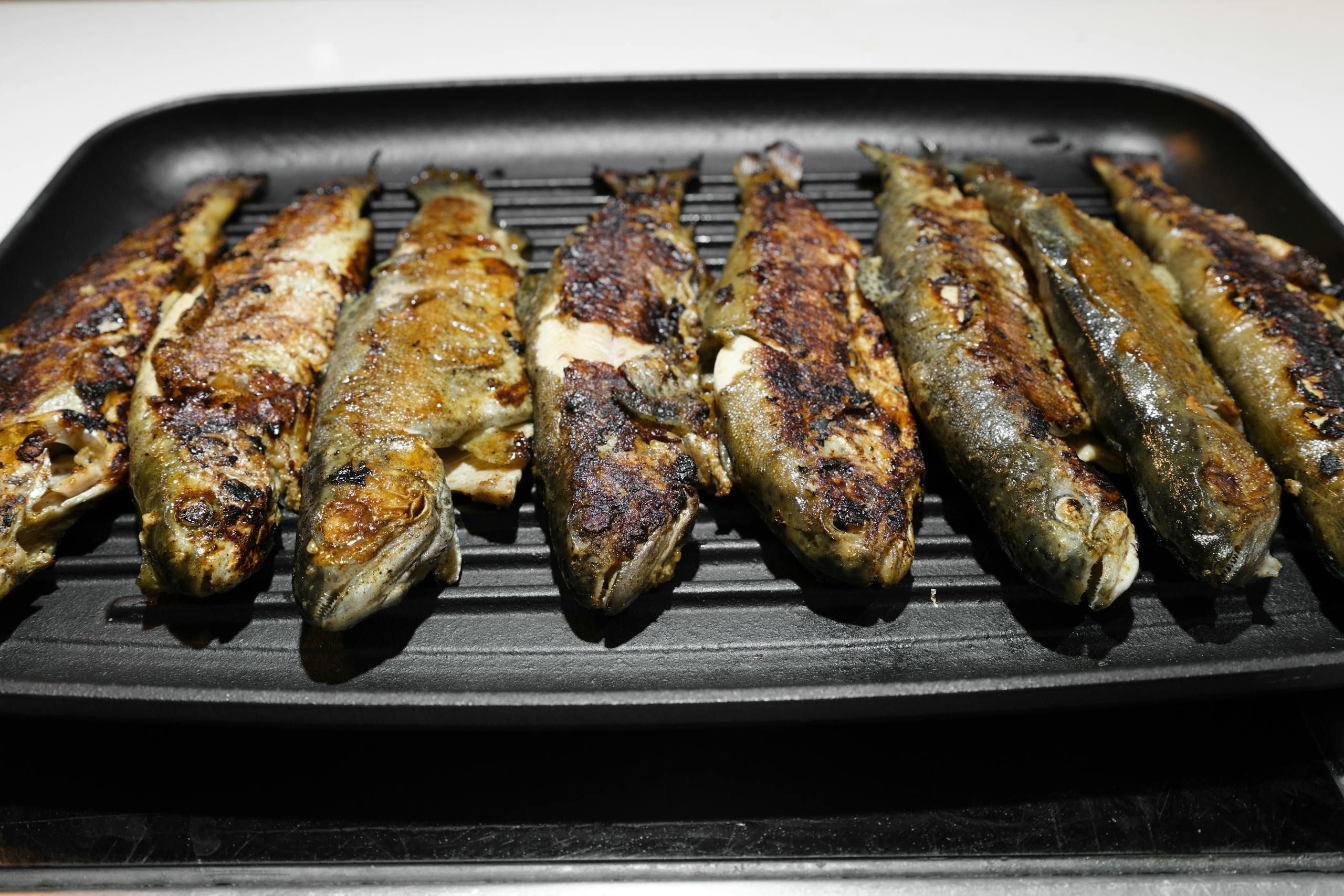 Close-up of grilled fish on a tray, showcasing delicious, crispy textures.