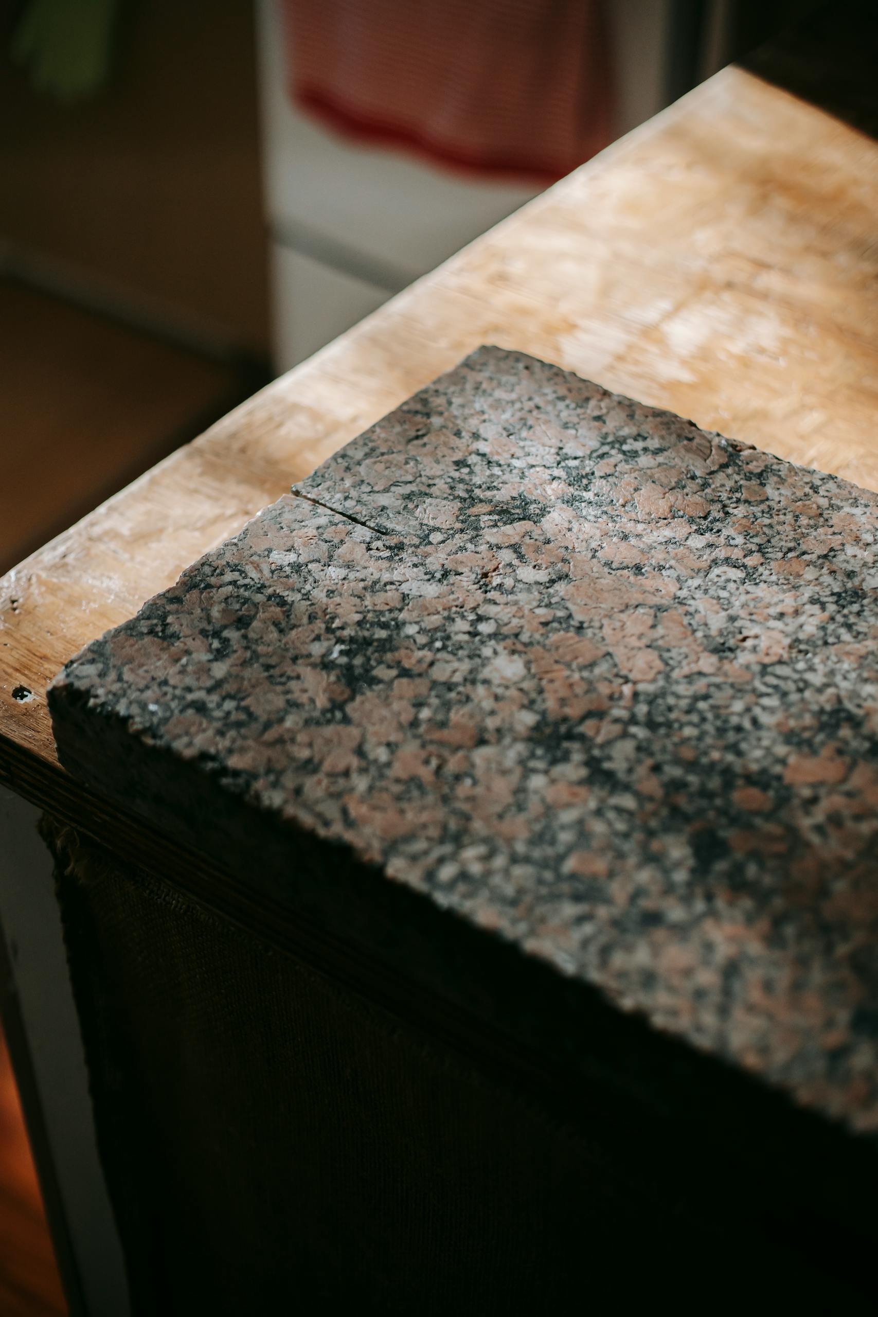 From above shabby brown plate made of granite placed on natural wooden surface in sunrays on blurred background