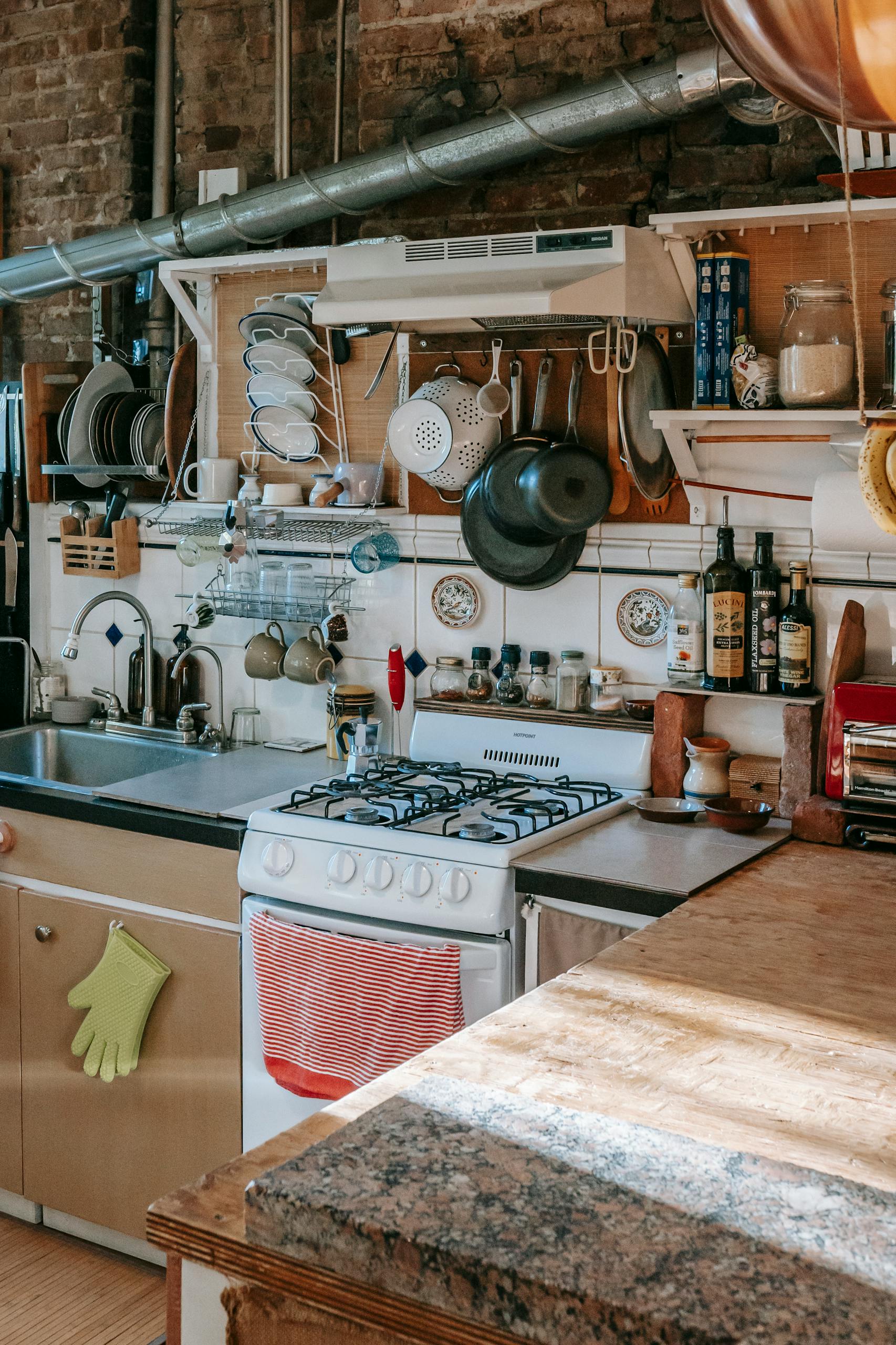 Masonry kitchen furnished with rustic kitchen units and filled with many kitchenware and utensils in sunlight