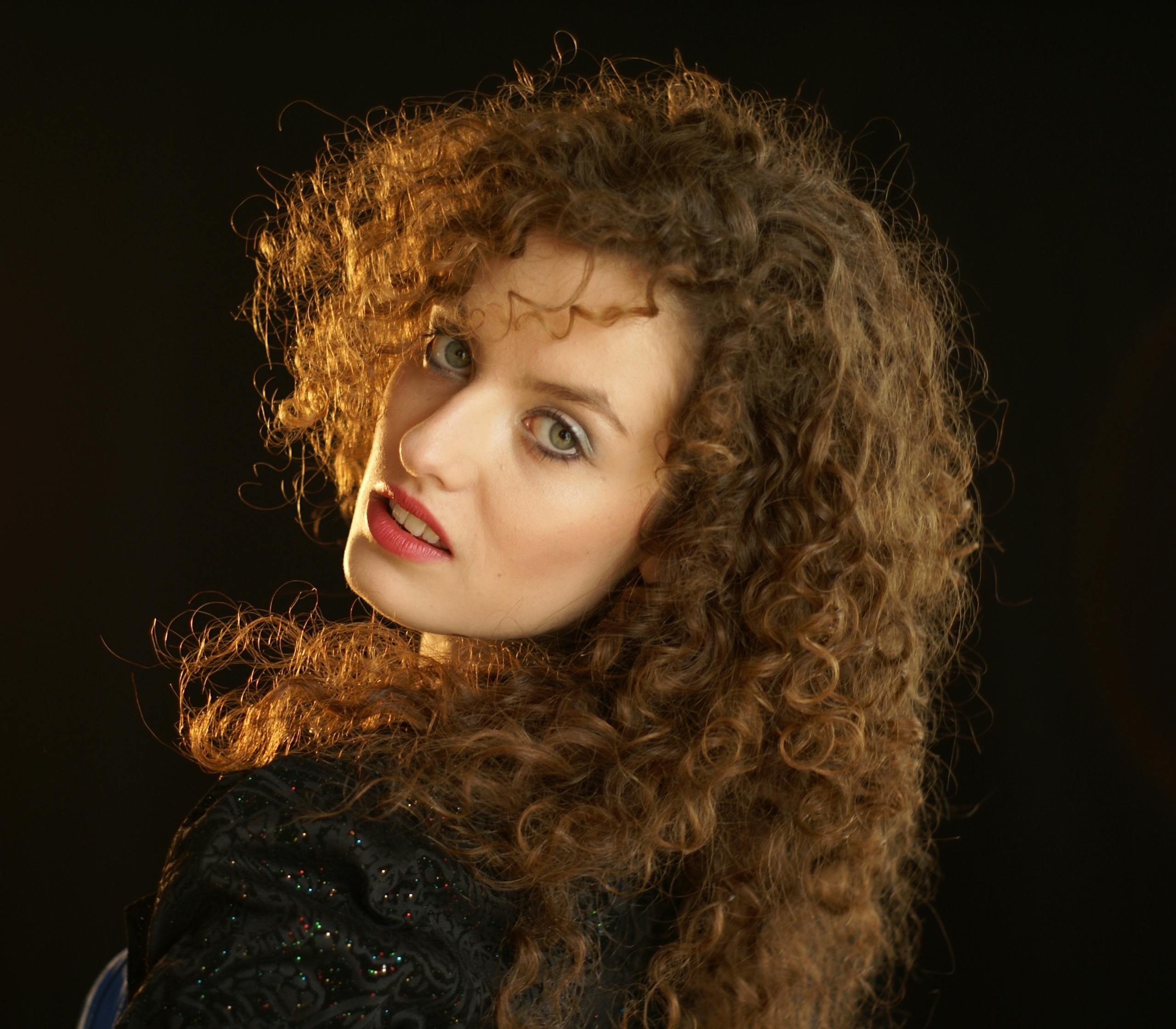 Stunning portrait of a woman with curly hair in an elegant pose, showcasing beauty and fashion.