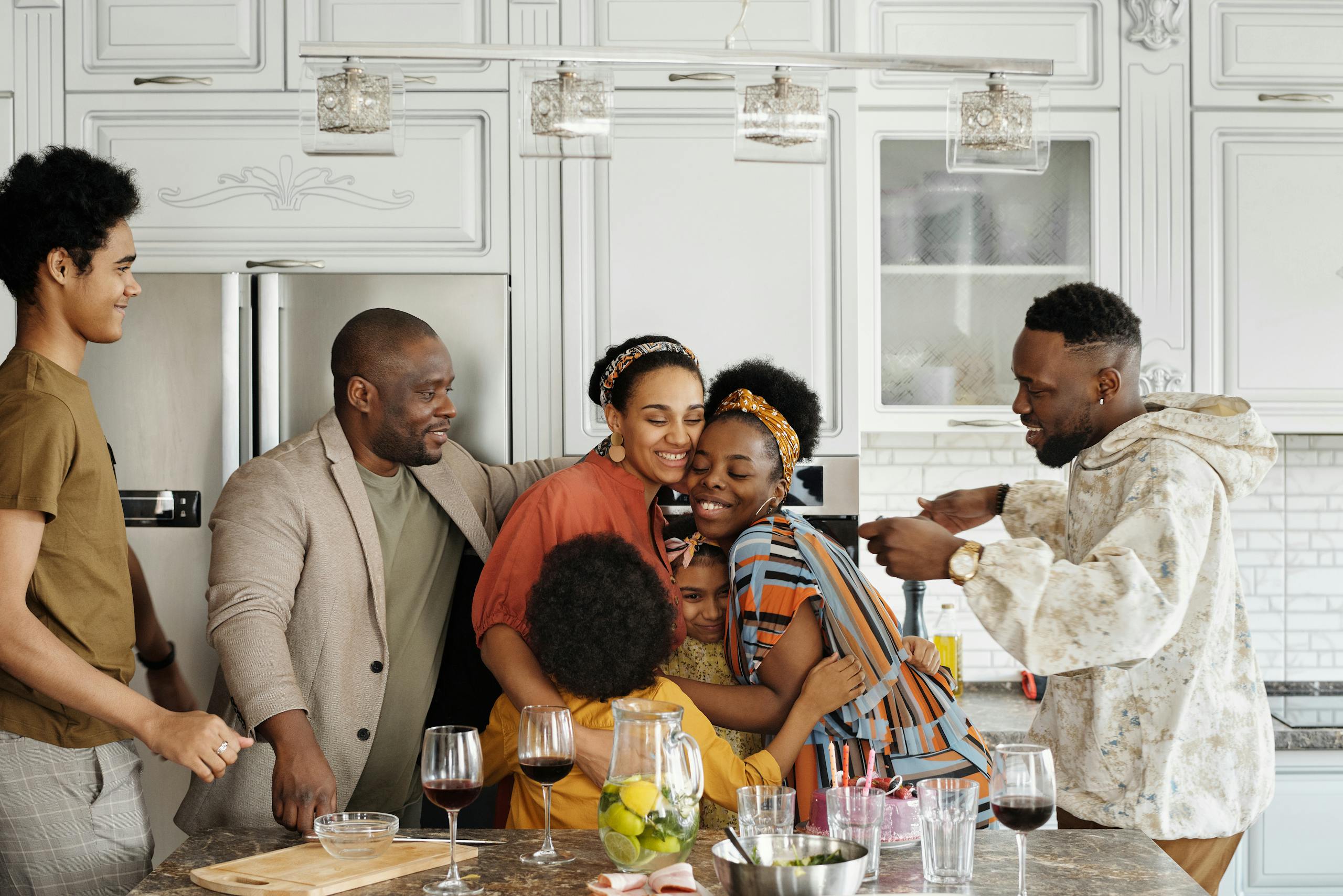 A joyful family gathering in a kitchen, embracing and smiling during a celebration.