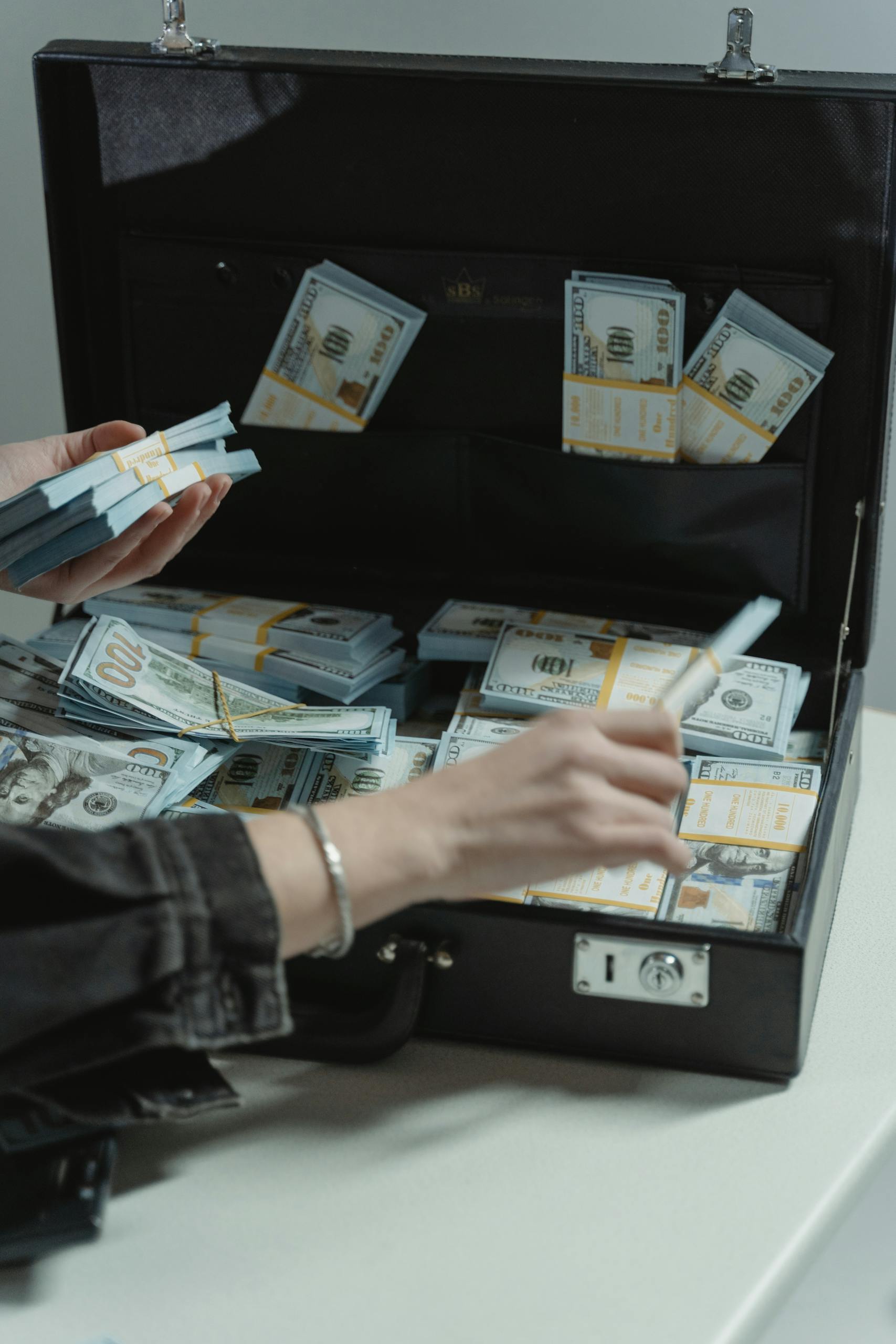 Close-up of organized bundles of cash in an open briefcase being handled.
