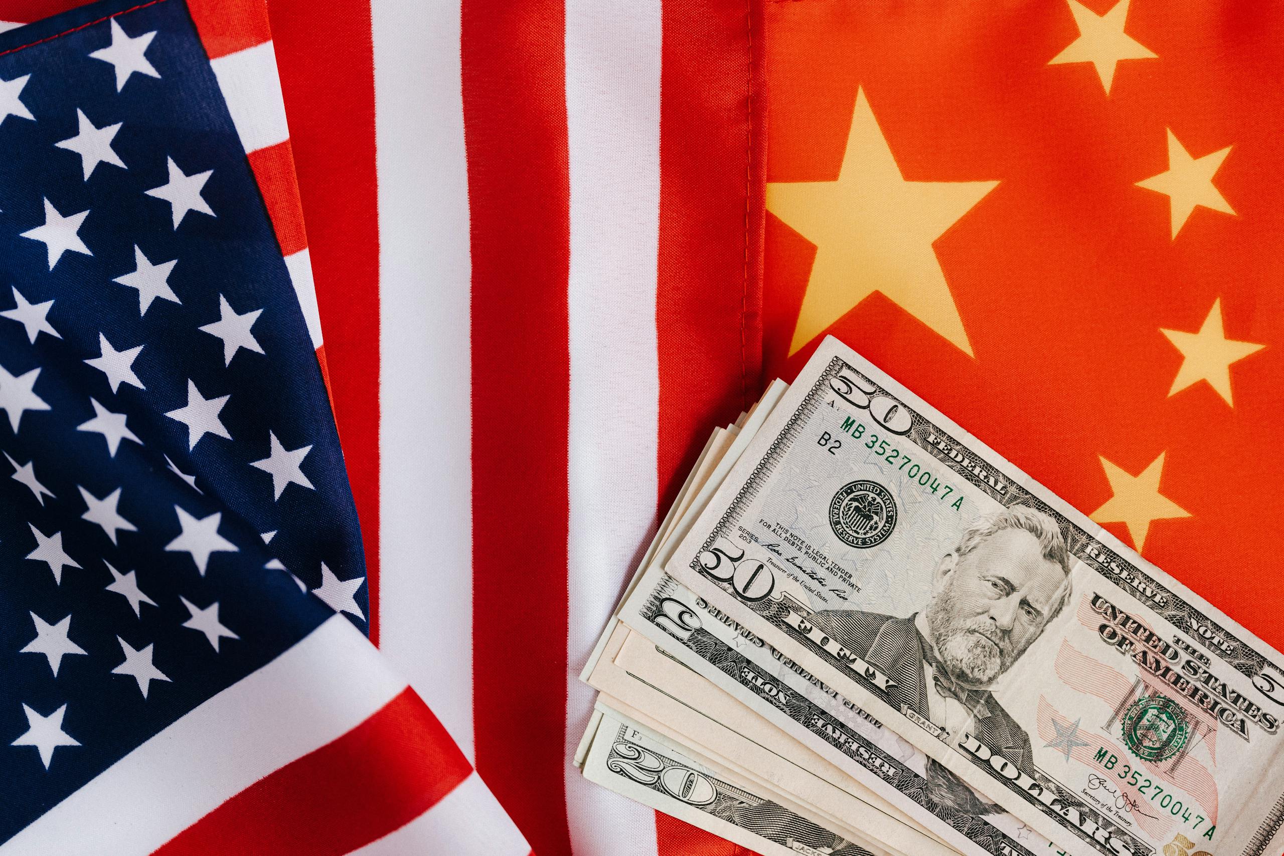 From above of United States banknotes placed on national flags of America and China illustrating international trade concept