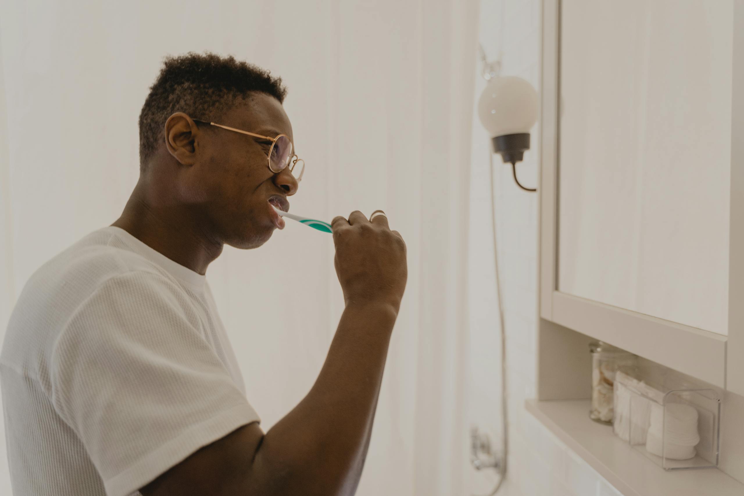 Man brushing his teeth in a bathroom, focusing on daily oral care and hygiene.
