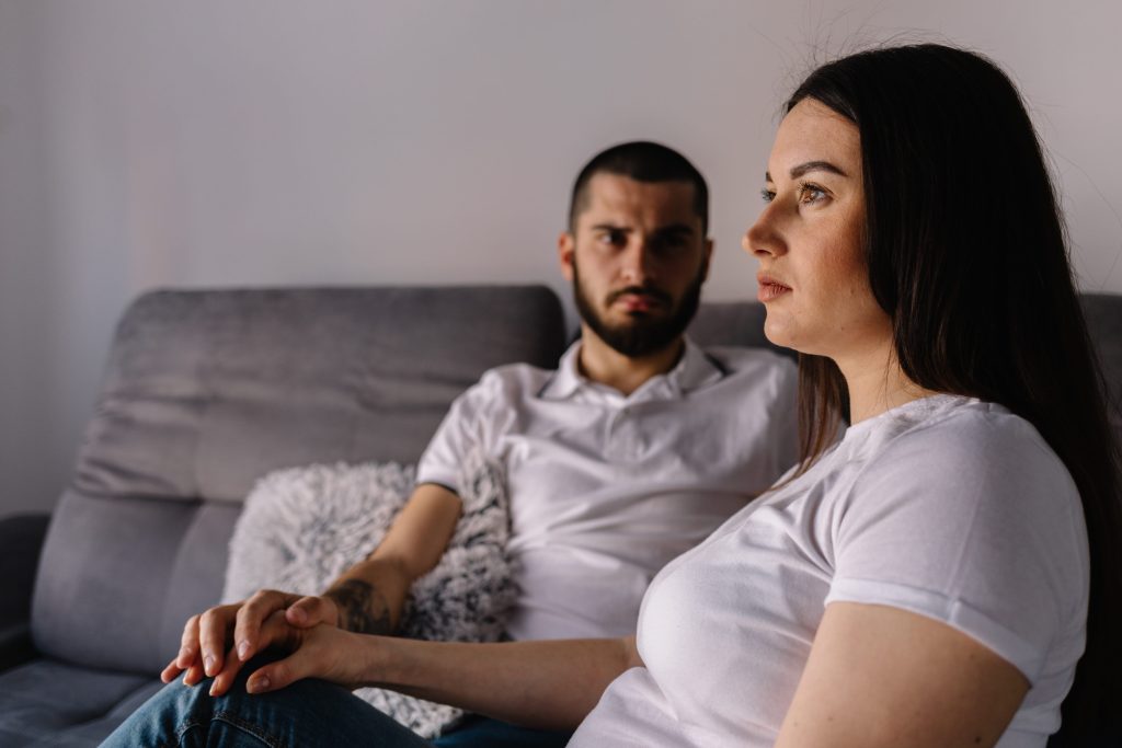 Couple dreaming to be parents. Upset man comforting his depressed wife with negative pregnancy test, free space