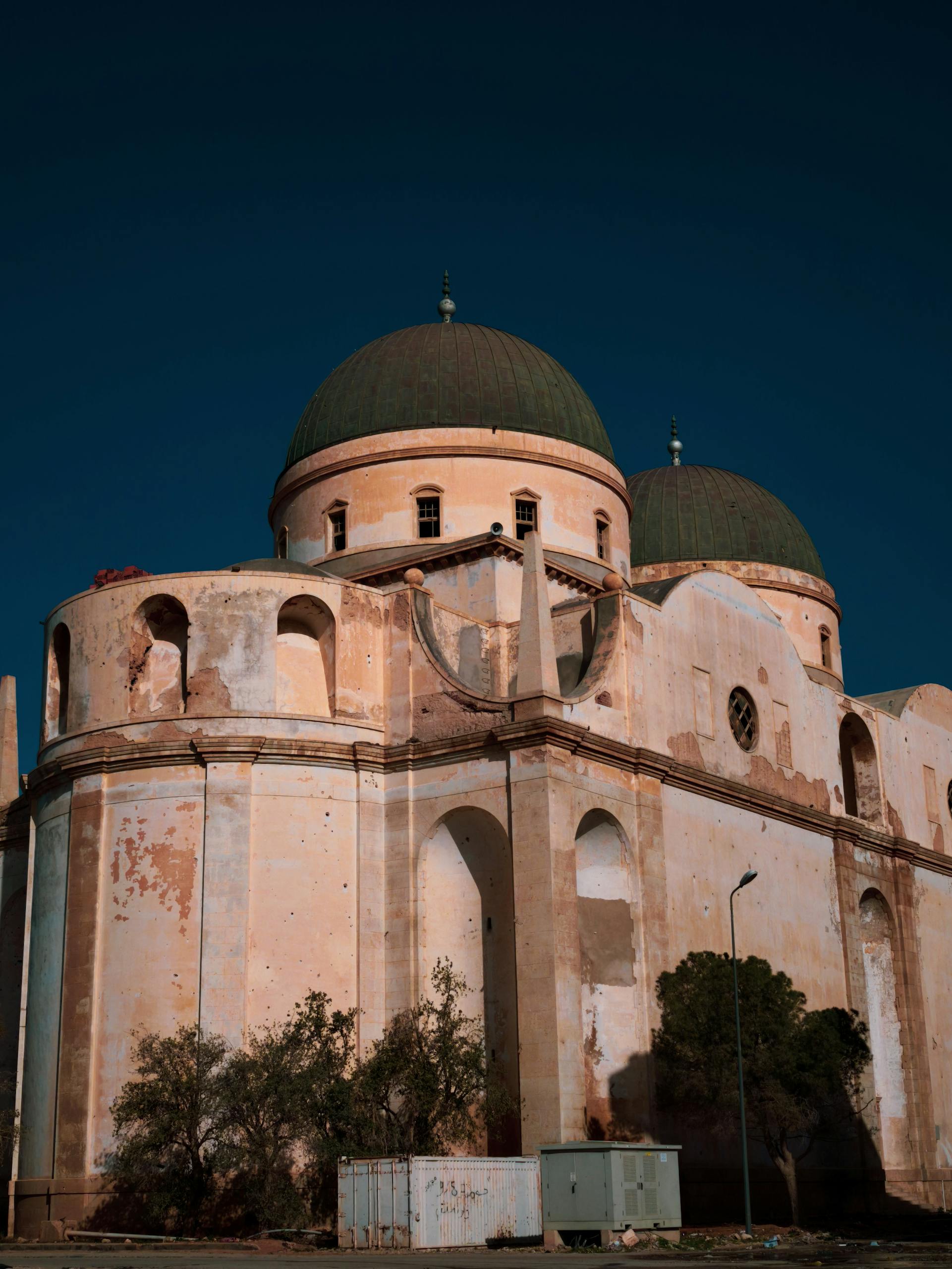 A striking old building with impressive domes against a clear blue sky in Libya.