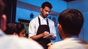 Attentive waiter writing down a customer's order in a cozy indoor restaurant.
