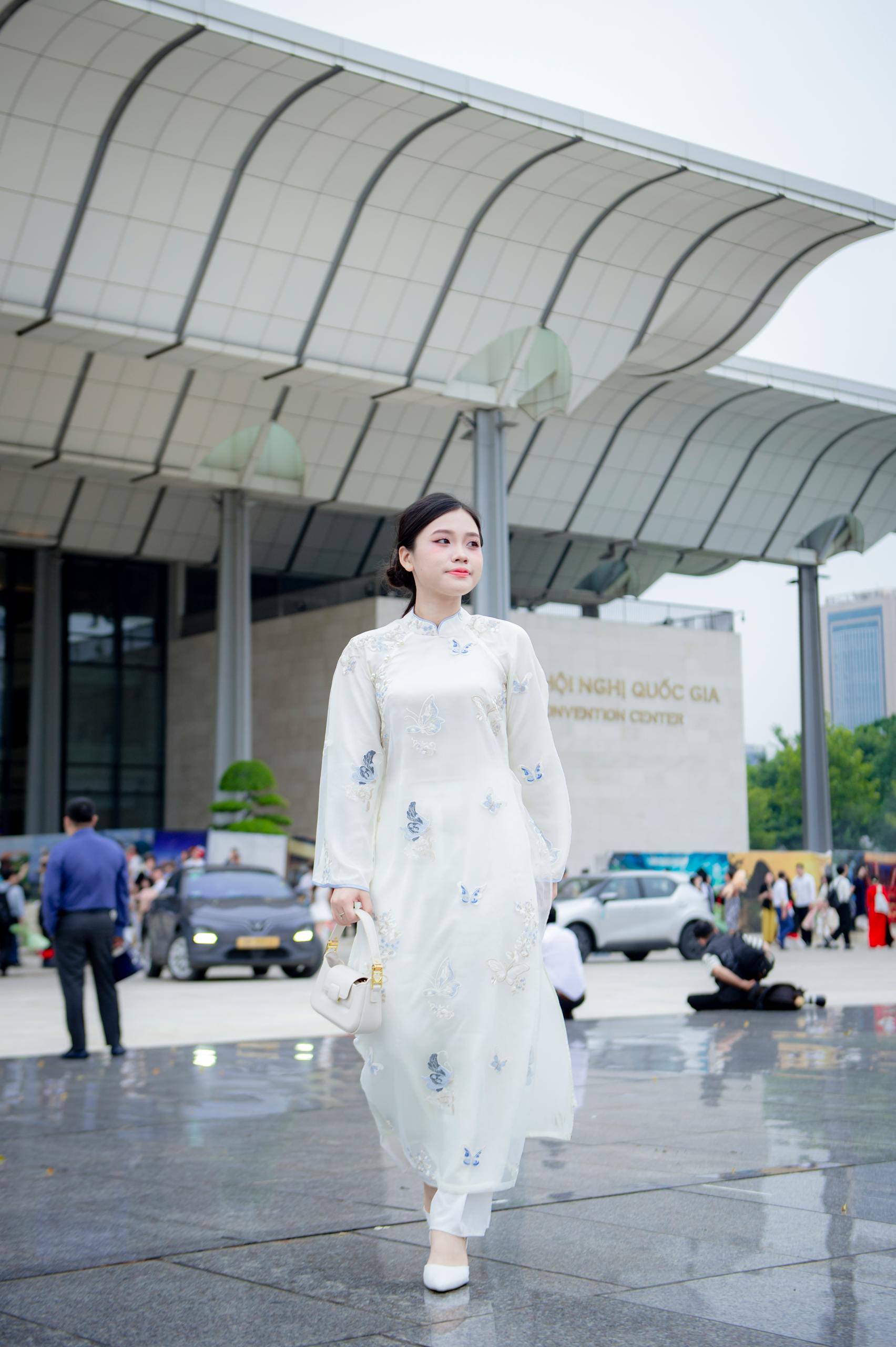 Elegant woman in traditional Vietnamese dress outside Vietnam National Convention Center, Hà Nội.