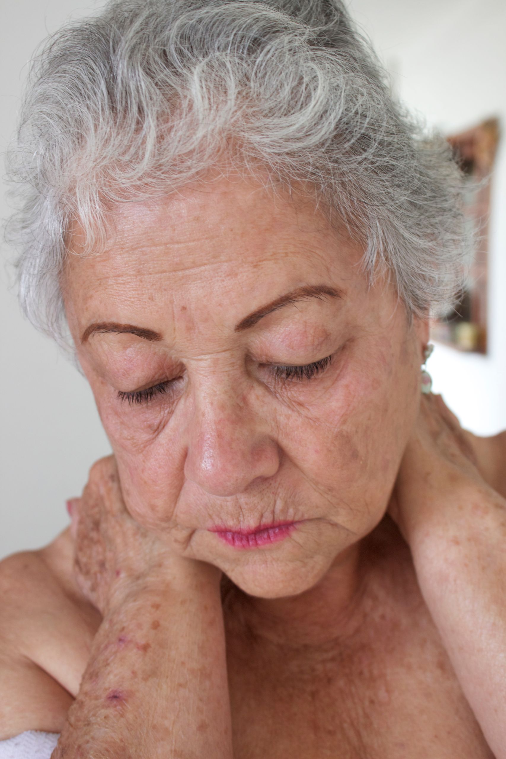 Portrait of an elderly woman with gray hair and closed eyes, expressing contemplation and serenity.