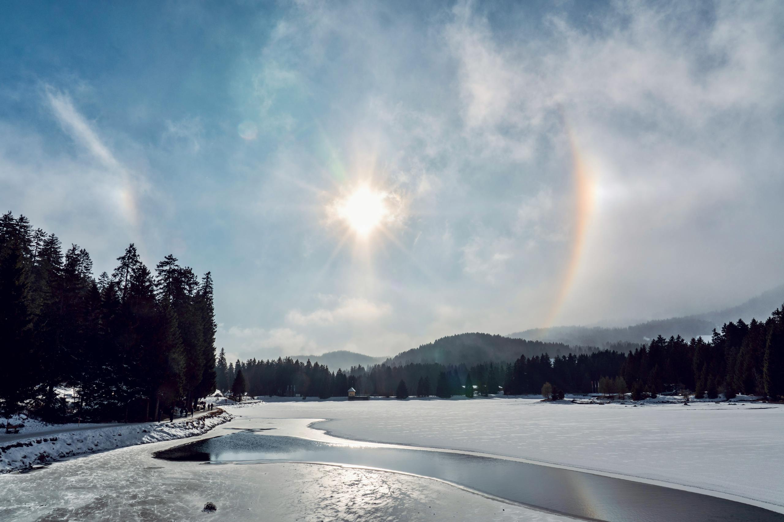 Stunning view of a sun halo over a winter landscape with a frozen lake.
