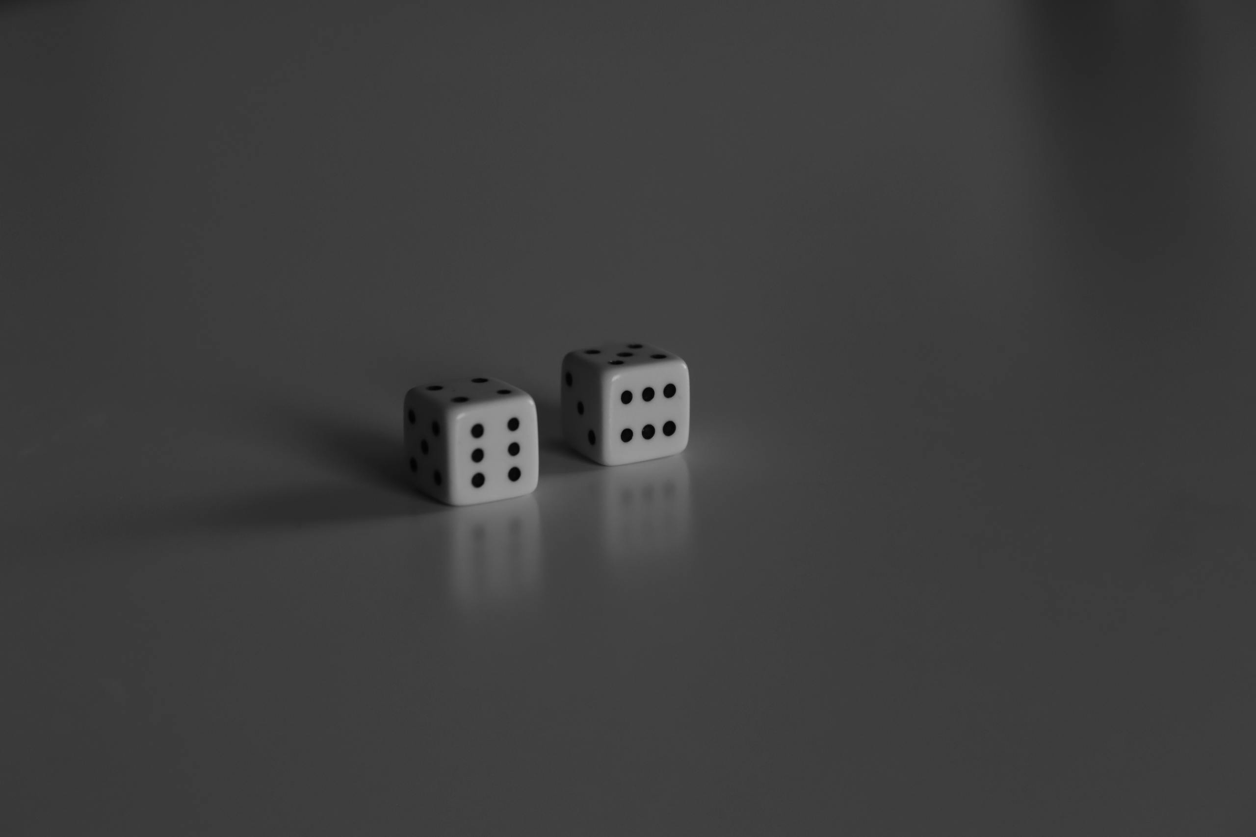 Two dice on a reflective surface in a minimalist black and white style.