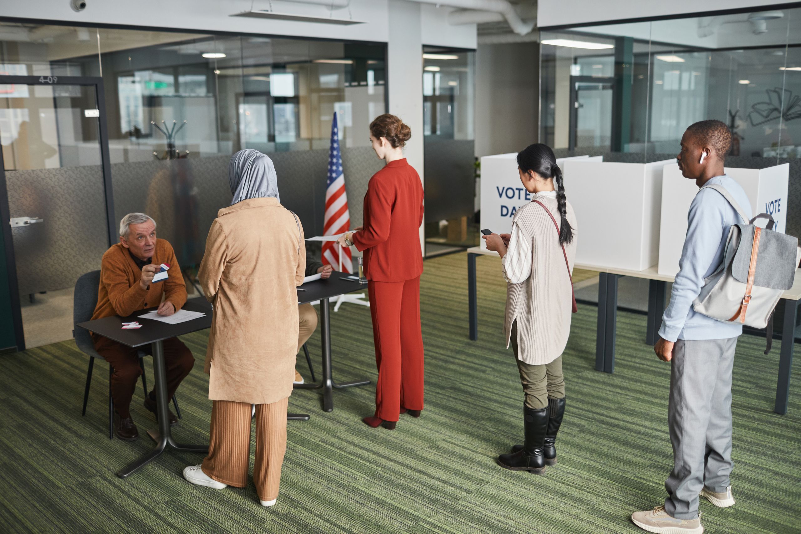 Diverse group of voters lining up at an indoor polling station on election day.