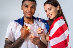 Young multicultural couple celebrating Independence Day with sparklers.