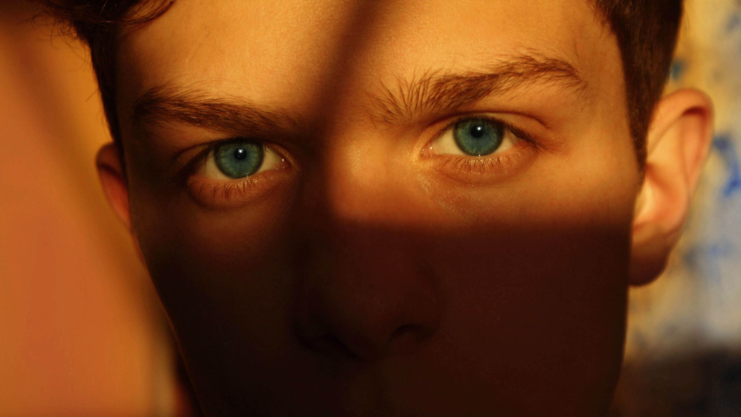 A captivating close-up portrait emphasizing blue eyes partly in shadow.