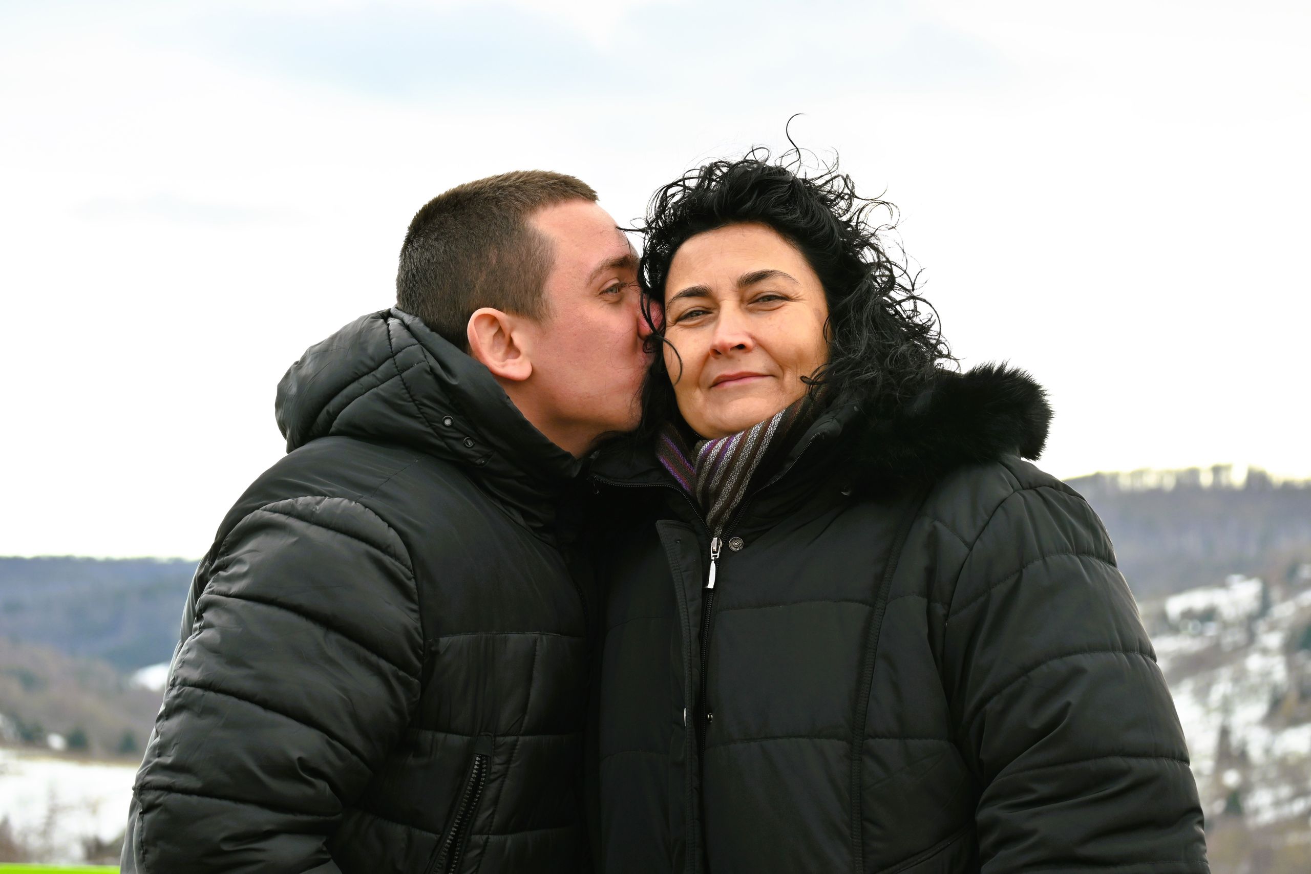 A heartwarming moment between a mother and son bundled up in winter coats outdoors.