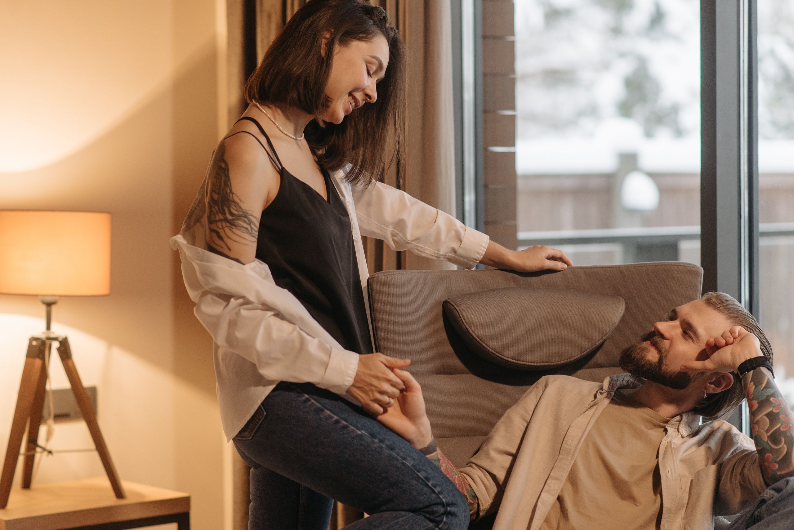 Caucasian couple sharing a tender moment indoors, holding hands by a window.