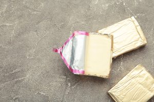 Processed cheese in foil on gray background. Top view