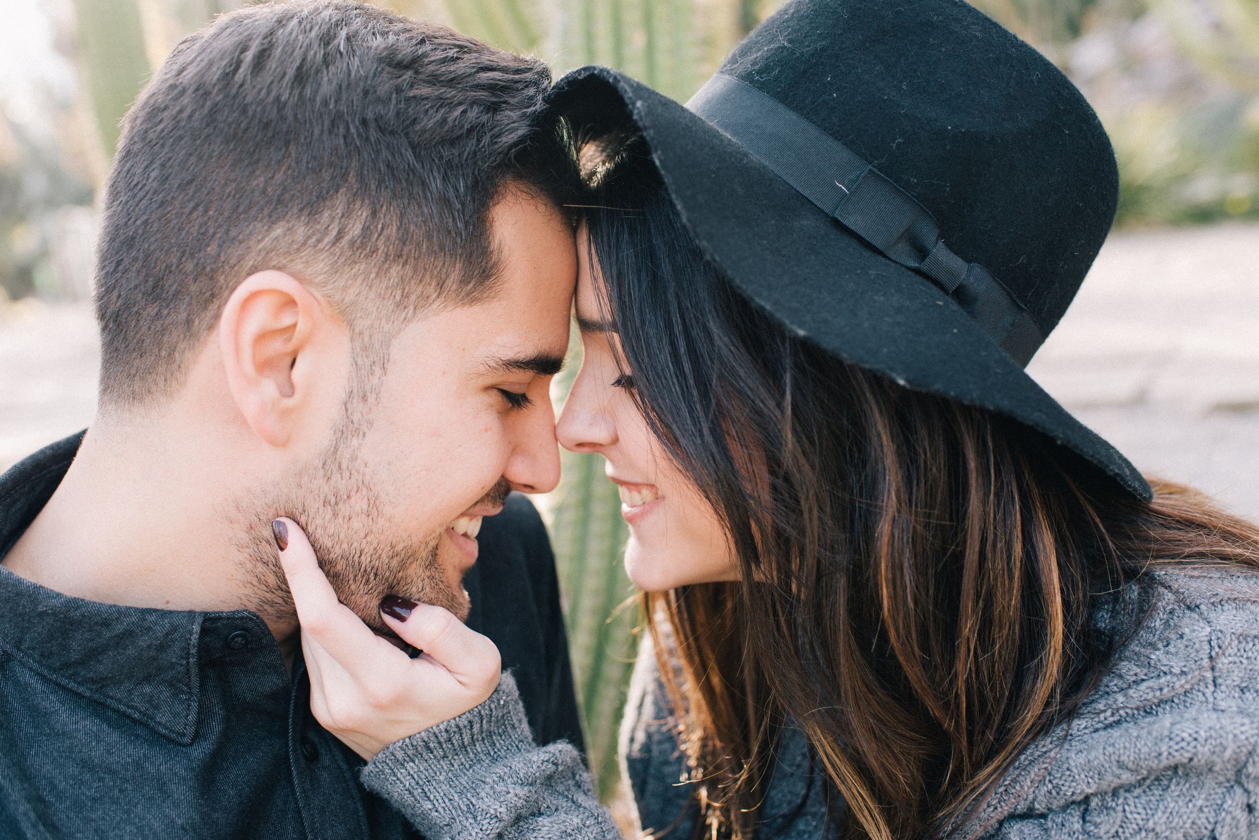 A joyful couple intimately close, smiling and sharing a tender moment outdoors.