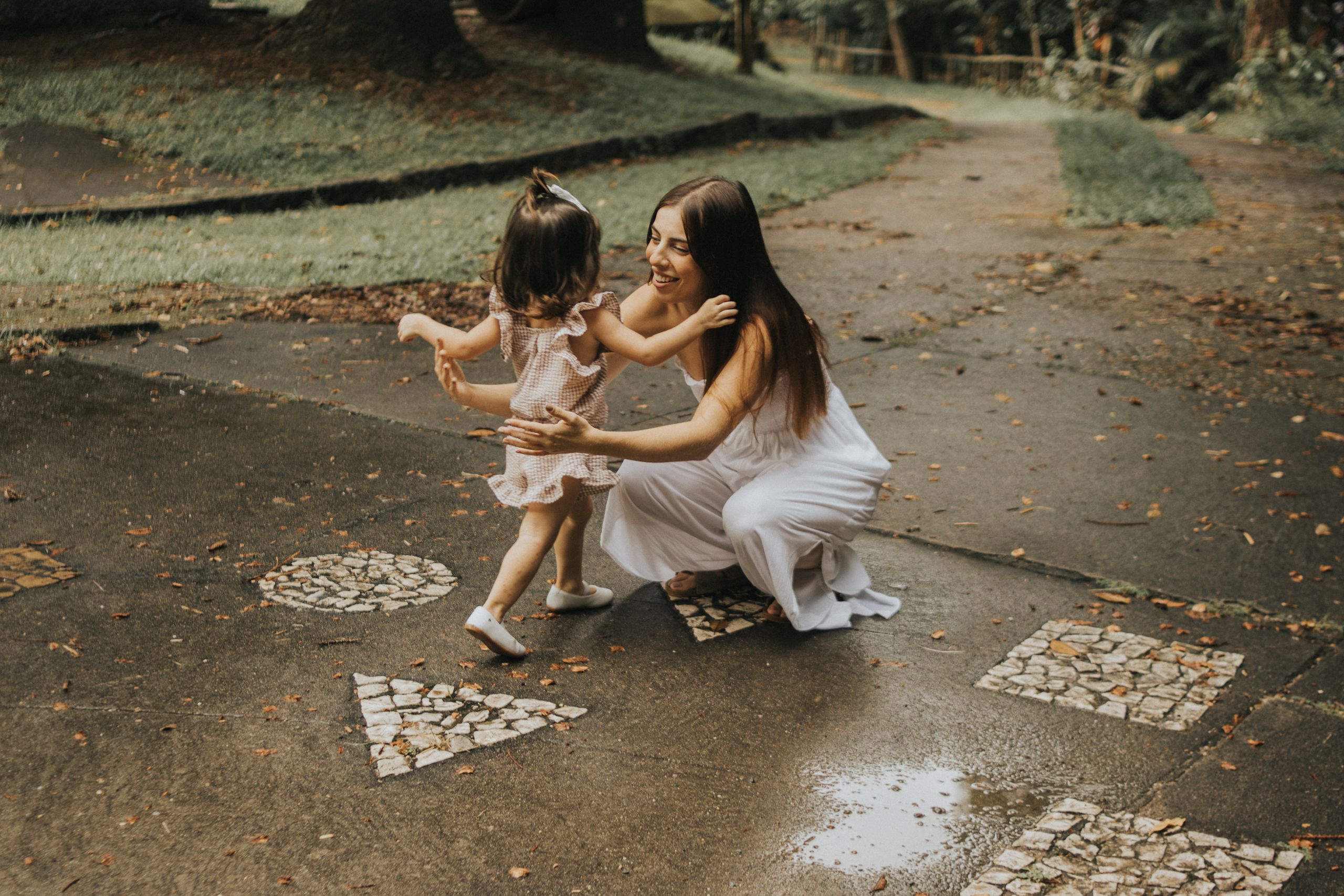 A joyful moment of a mother embracing her young daughter in a park setting.