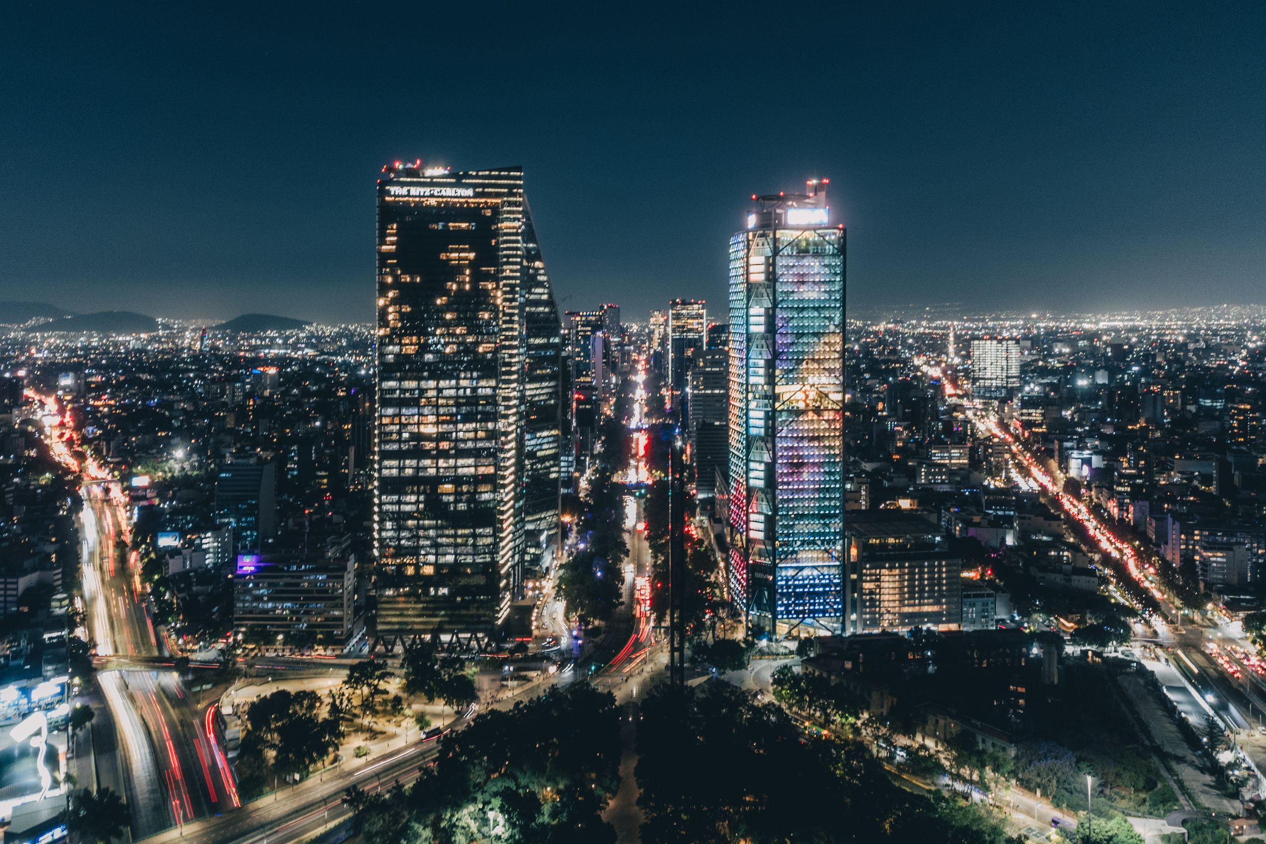 Aerial view of illuminated skyscrapers at night in Mexico City, showcasing vibrant city life.