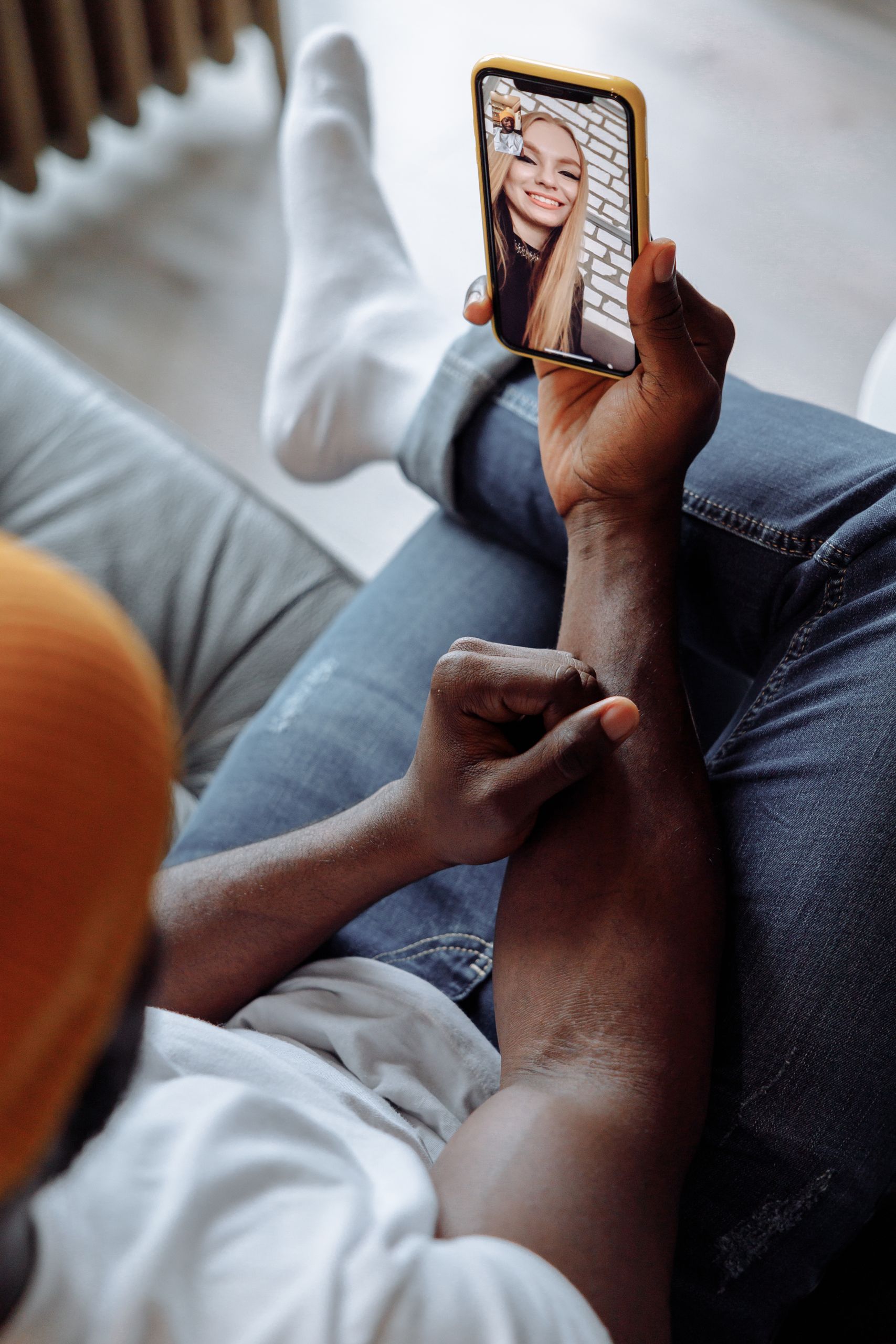 Black man relaxing on a couch during a video call on a smartphone, showcasing modern communication.