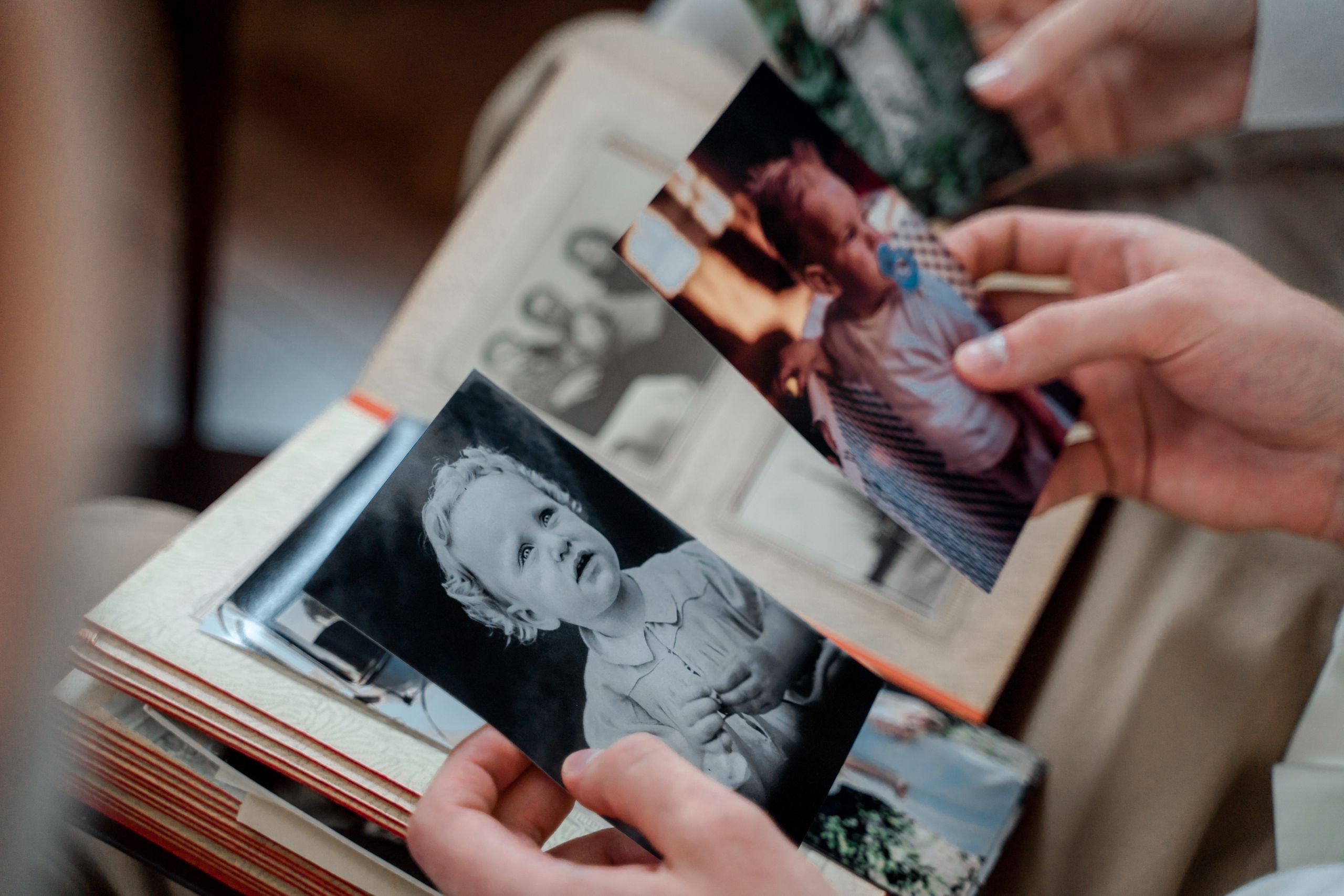 Close-up of hands examining nostalgic family photos in an album.
