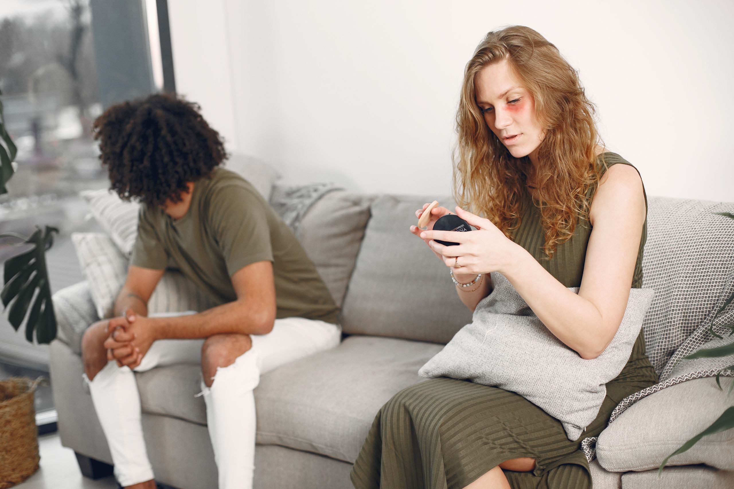 Couple sitting apart on a sofa, each lost in thought, highlighting relational tension.