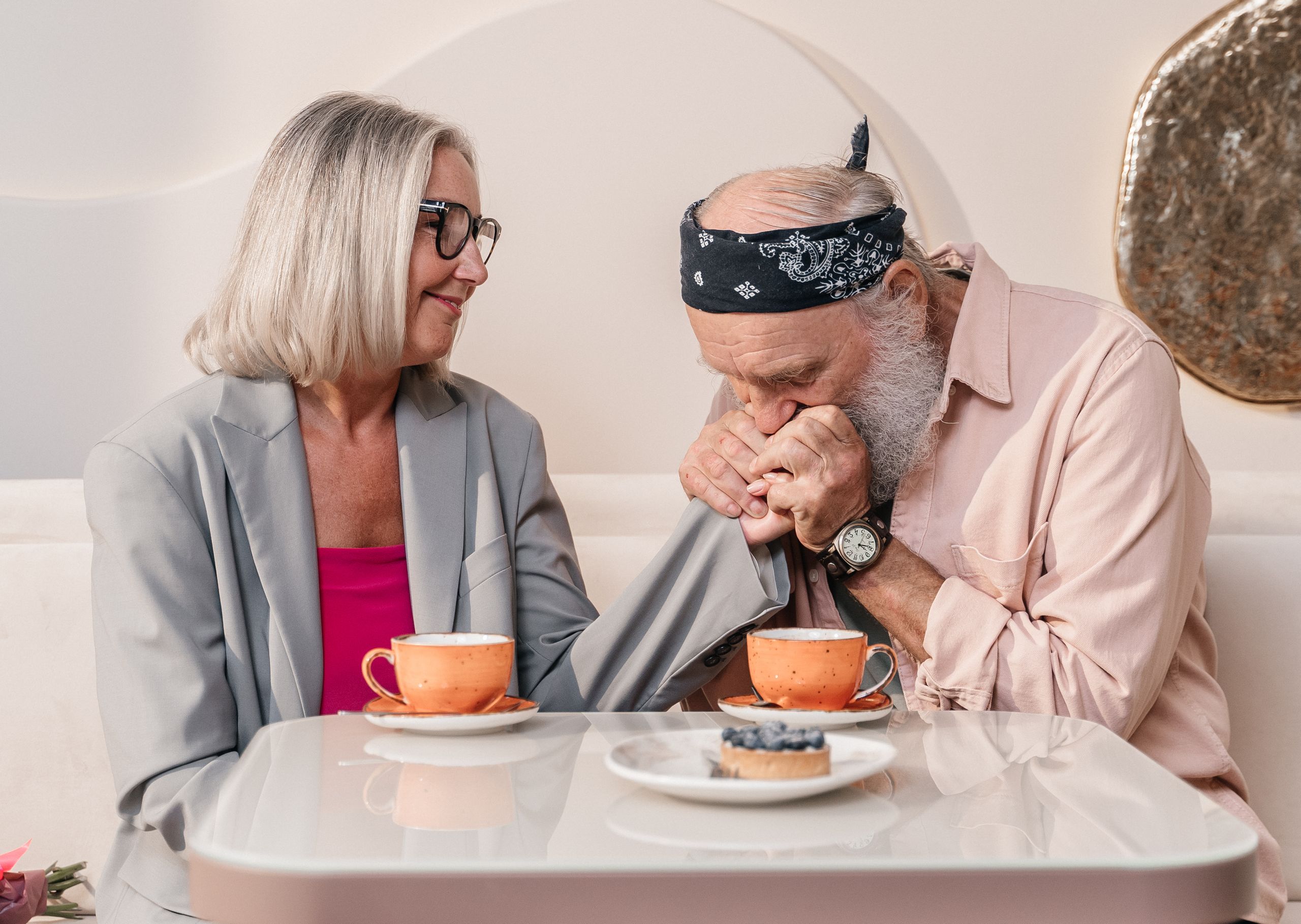 Elderly couple enjoying a warm moment at a cafe, sharing coffee and affection.