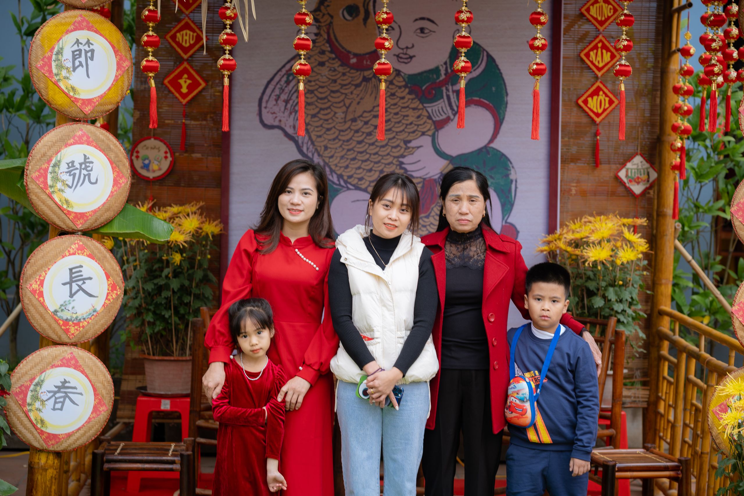 Family of five posing for a portrait in a colorful, traditional Vietnamese setting with festive decorations.
