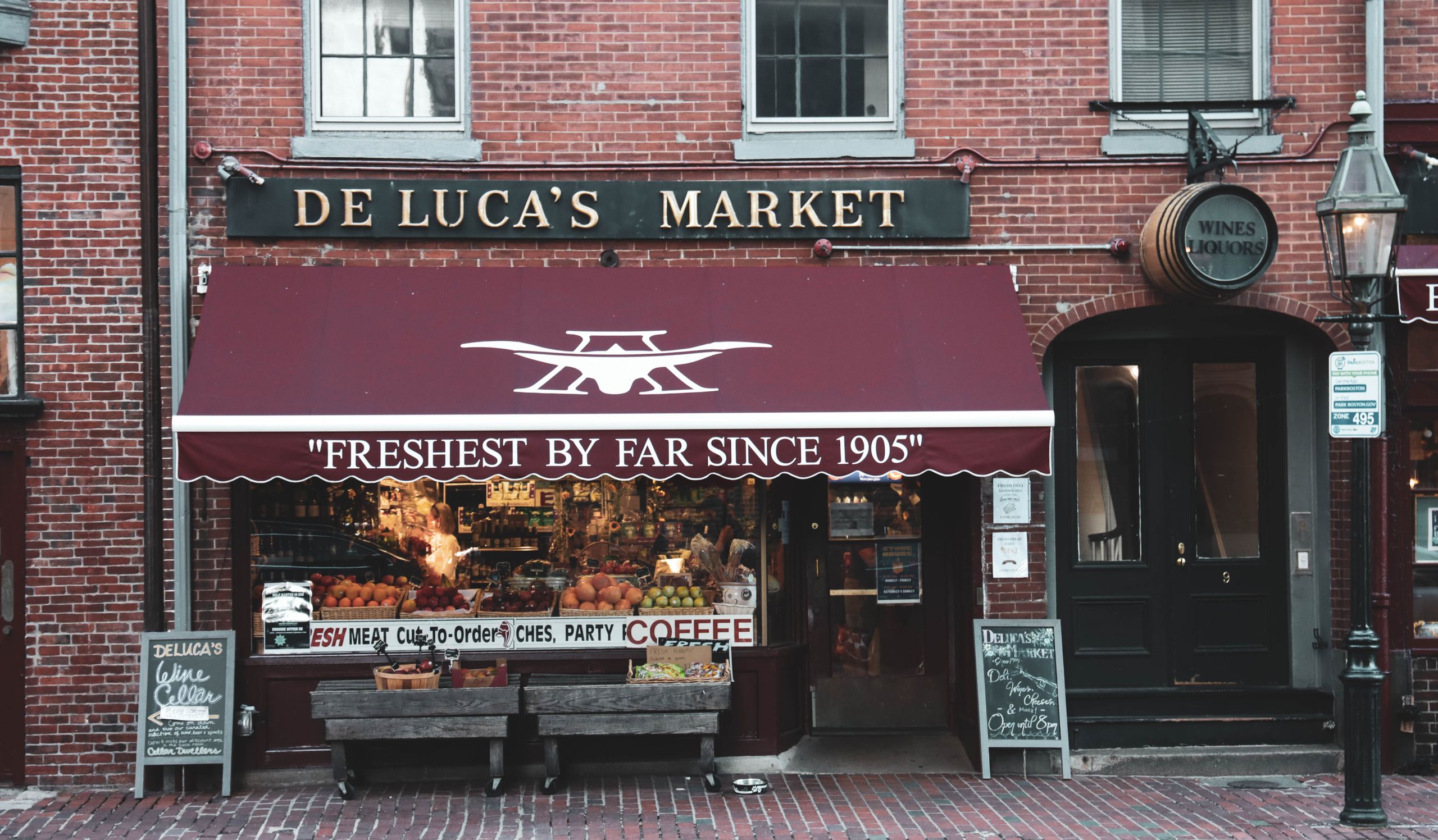 Historic De Luca's Market facade showcasing fresh produce and cozy urban atmosphere.