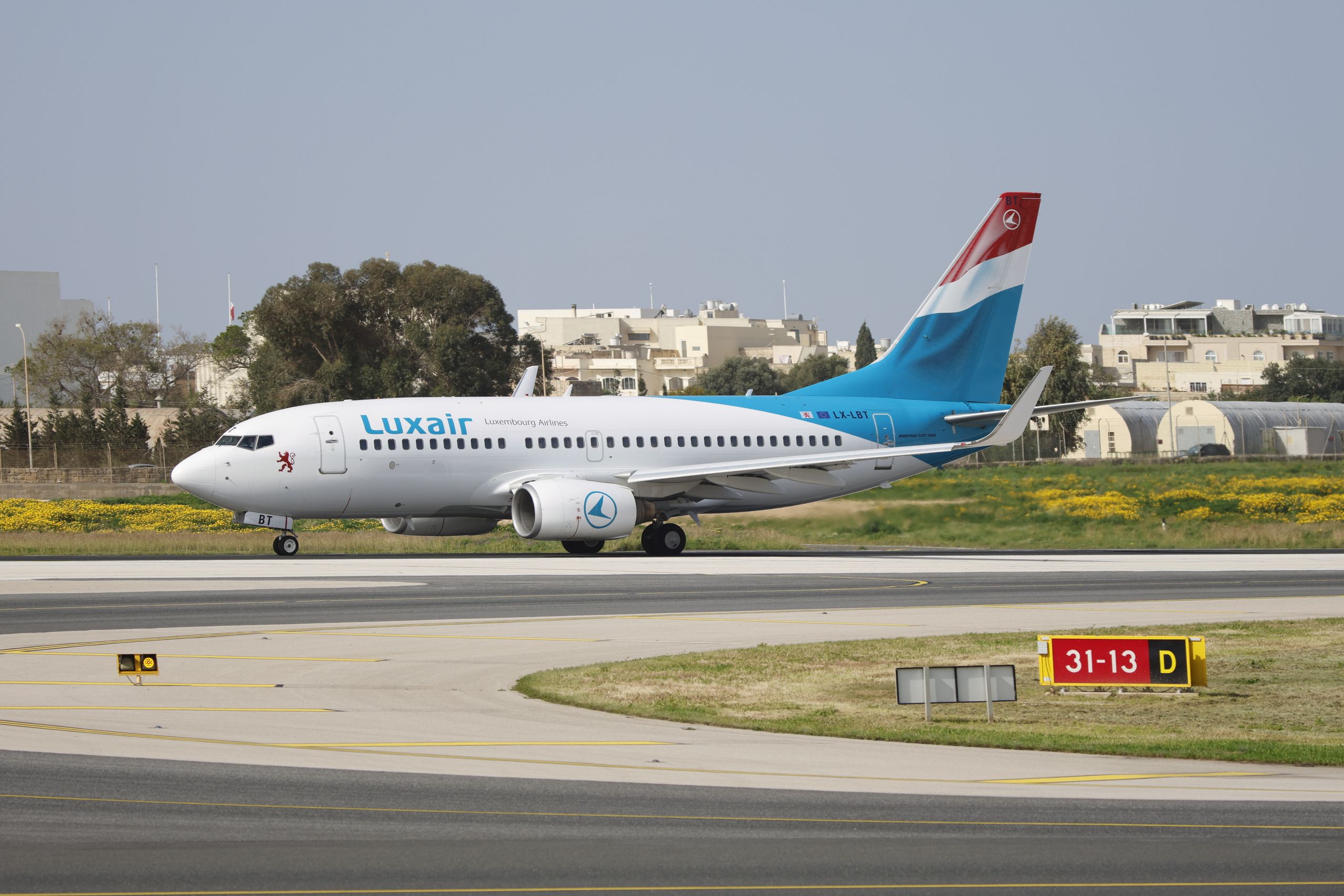 Luxair aircraft taxiing on runway at airport, showcasing travel and aviation themes.