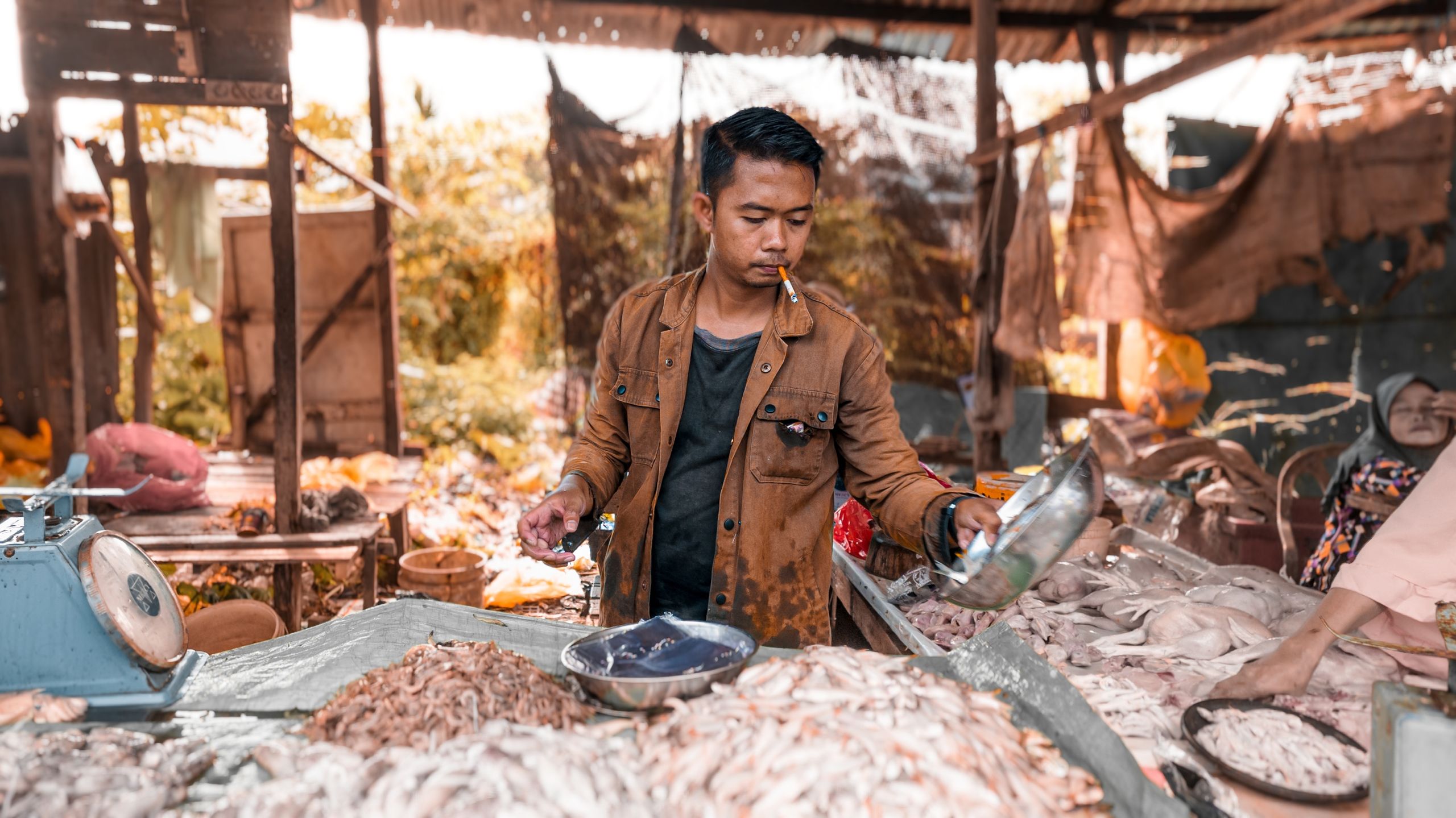 Man selling fresh seafood at an outdoor market stall in Pontianak, Indonesia.
