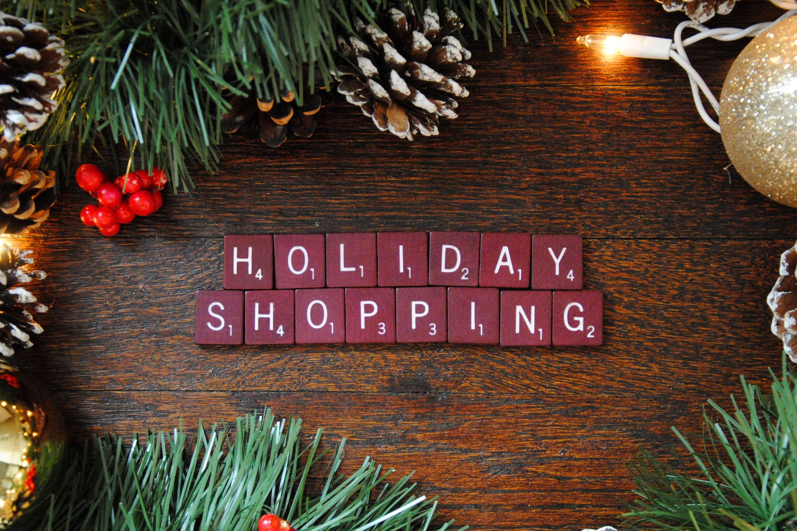 Top-down view of festive holiday shopping decoration with pine cones, berries, and lights.