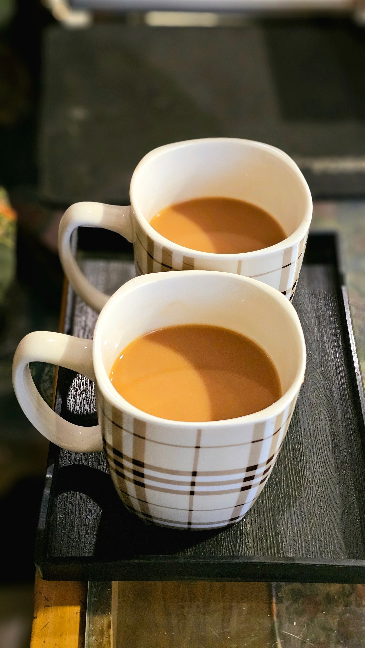 Two stylish mugs filled with steaming hot tea resting on a tray. Perfect for warmth and comfort.