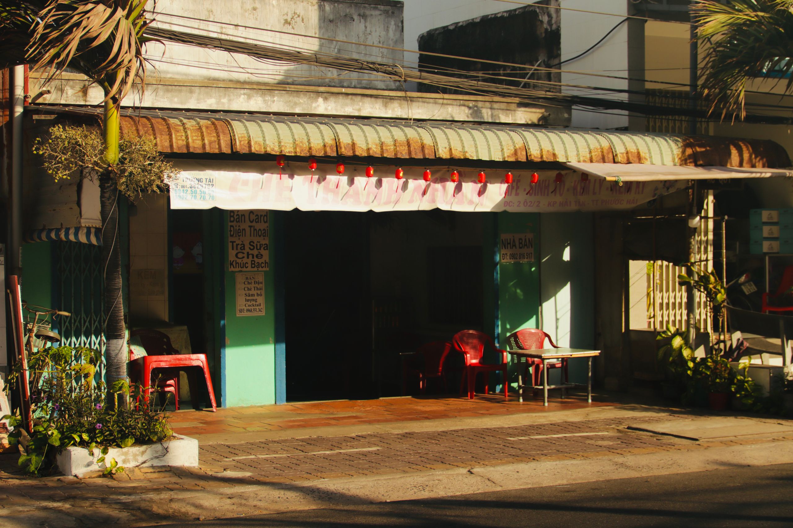 An inviting street view of a quaint urban cafe with outdoor seating and warm sunlight.