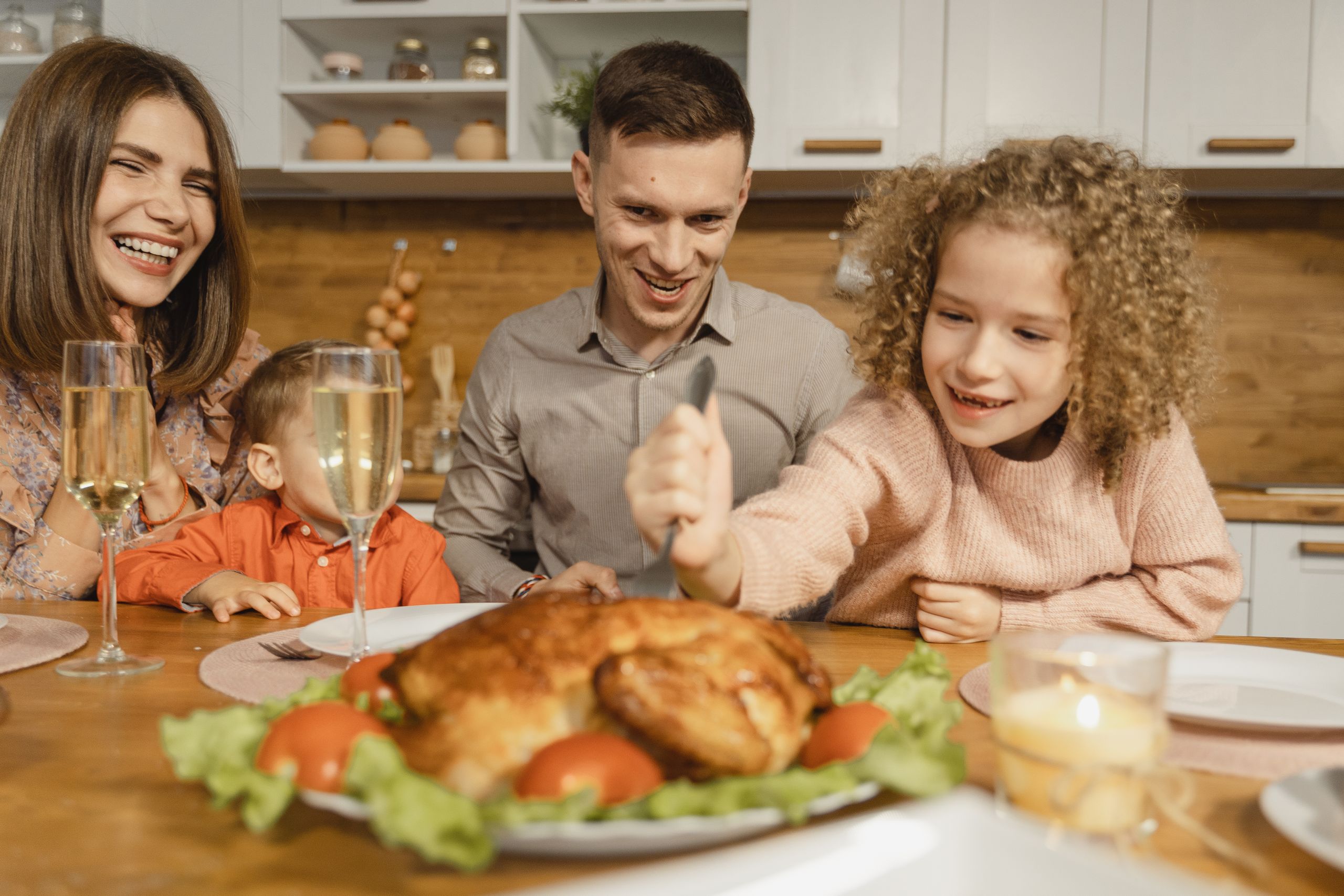 Family gathered around a dinner table enjoying a Thanksgiving meal with smiles and laughter.