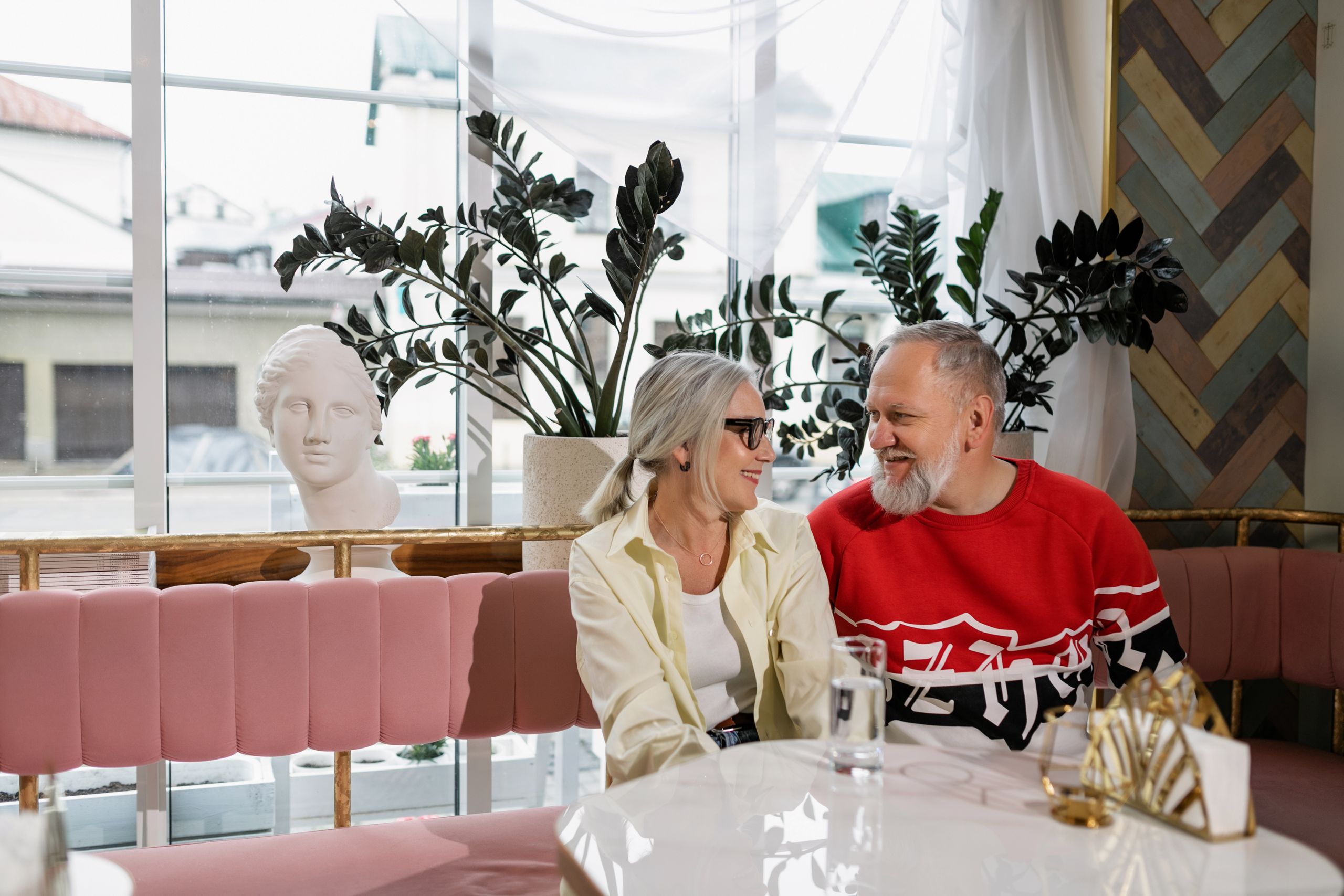 Senior couple enjoying a cozy moment in a stylish cafe, sharing laughter and affection.